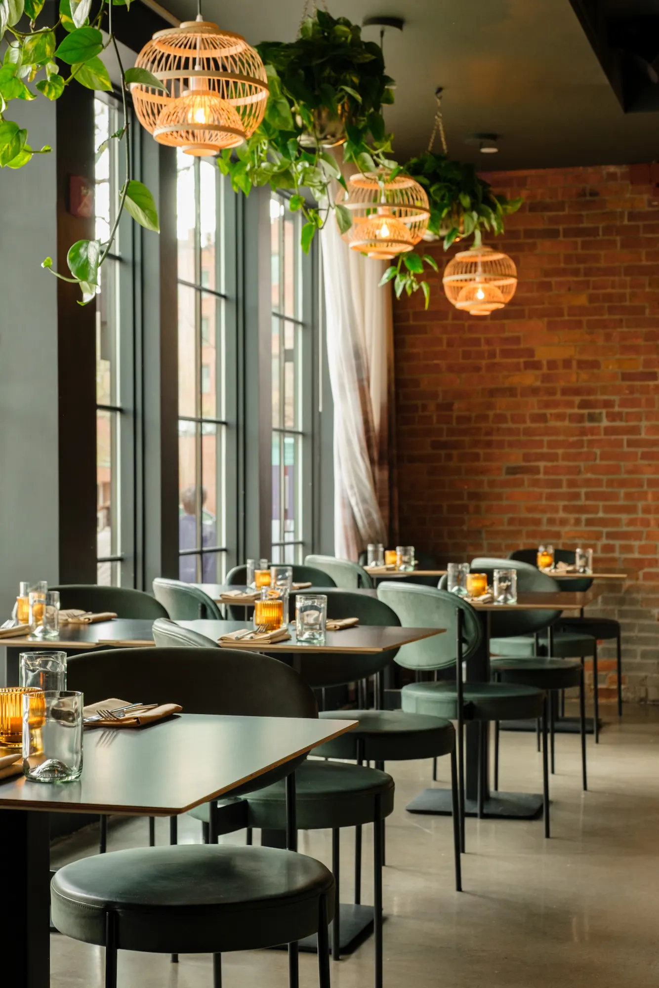 Tables along the tall windows, with the brick beyond.
