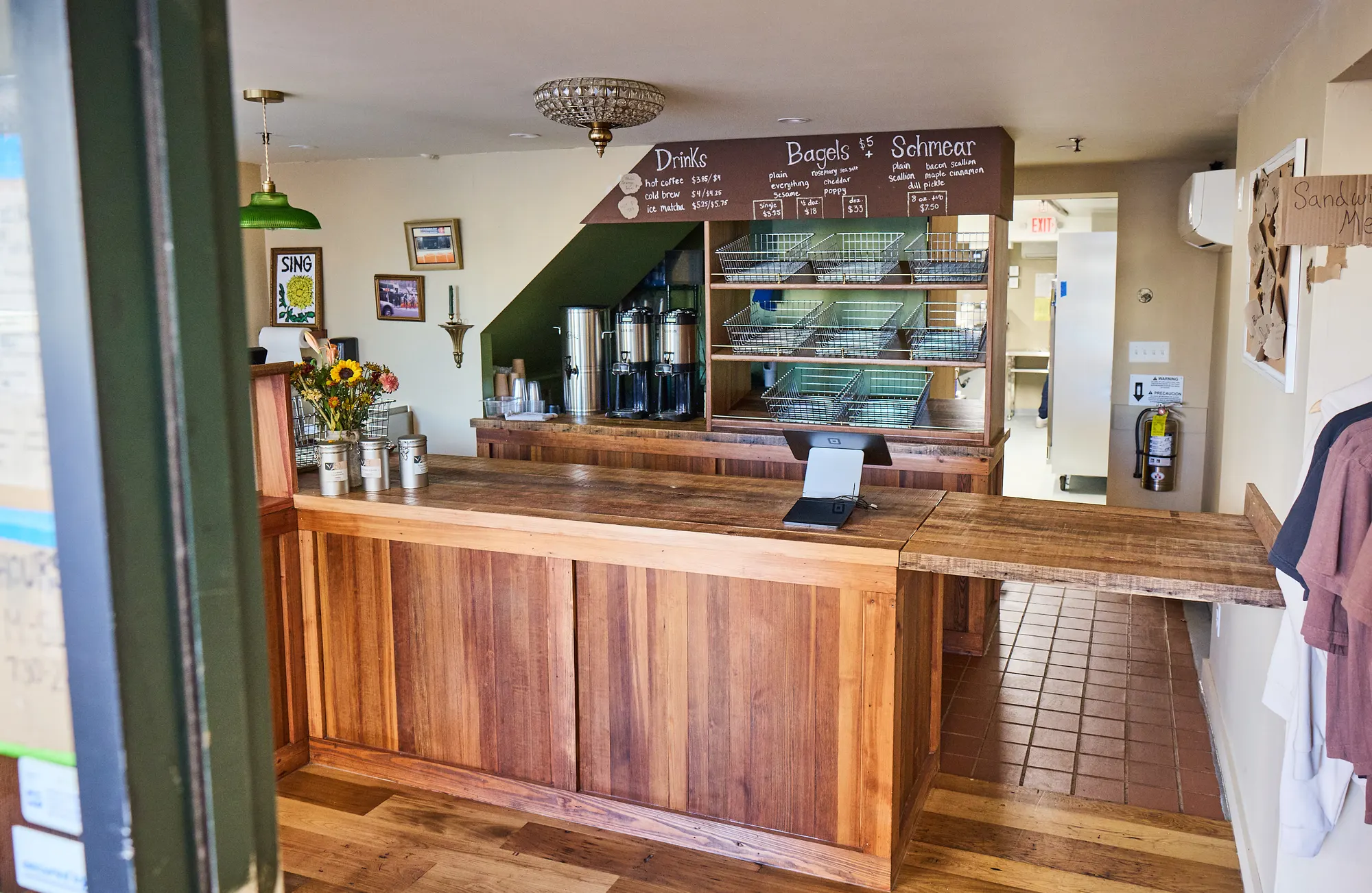 The counter, the menu wall and its baskets, seen from the door under a crystal ceiling light.