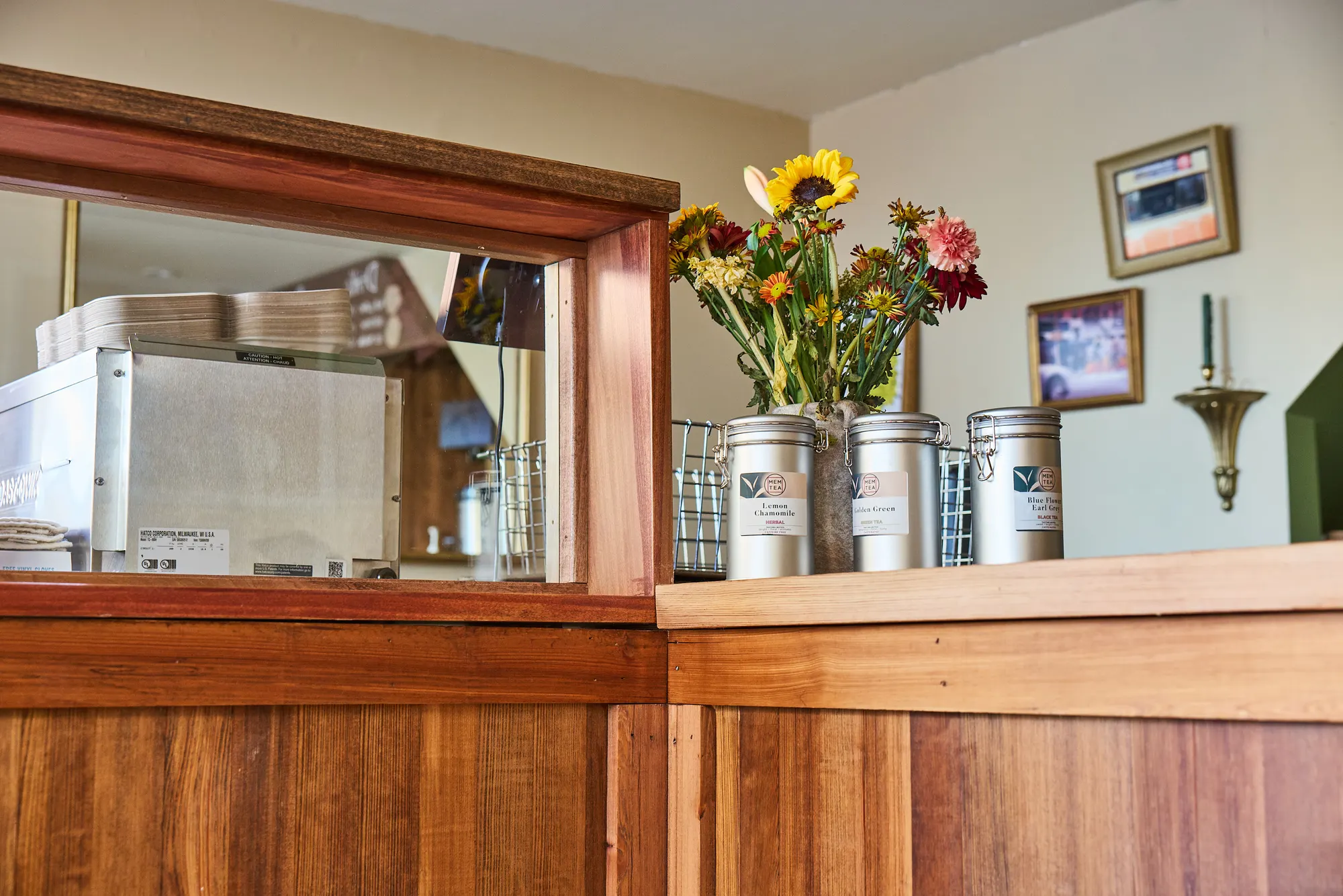 Sunflowers and steel tins on the counter, beside a window through to the kitchen.