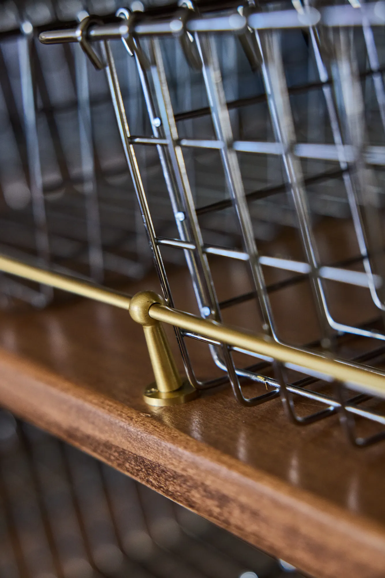 Wire baskets resting on a brass rail along a timber shelf.