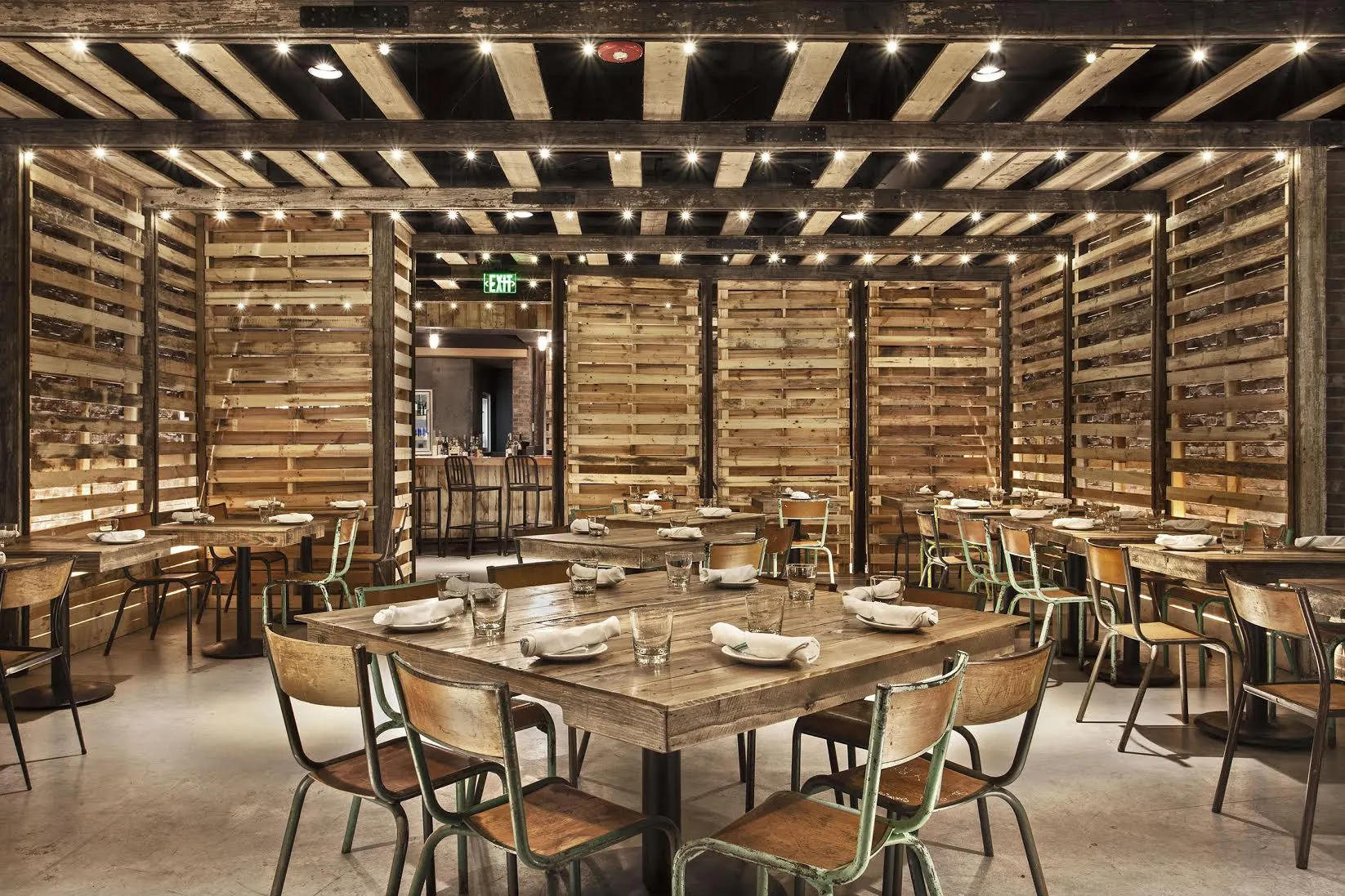 The dining room's tables under a slatted ceiling, enclosed by timber screens.