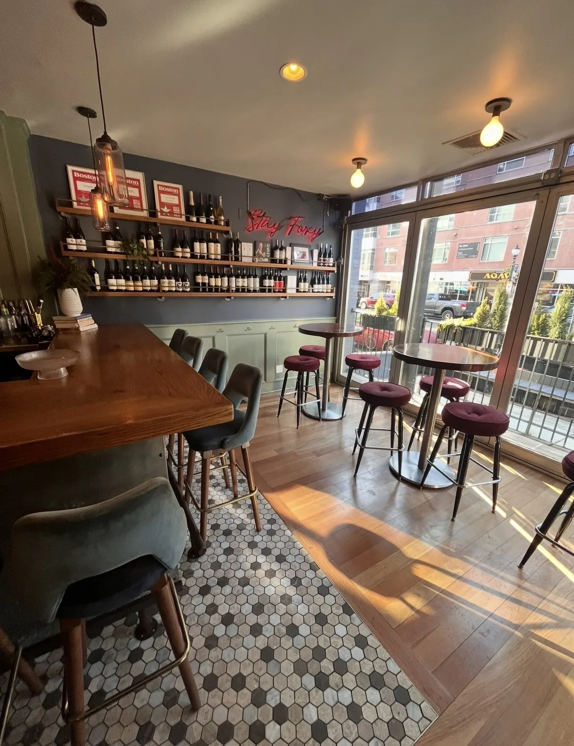 The end of the bar and high tables by the front windows, afternoon sun across the timber floor.