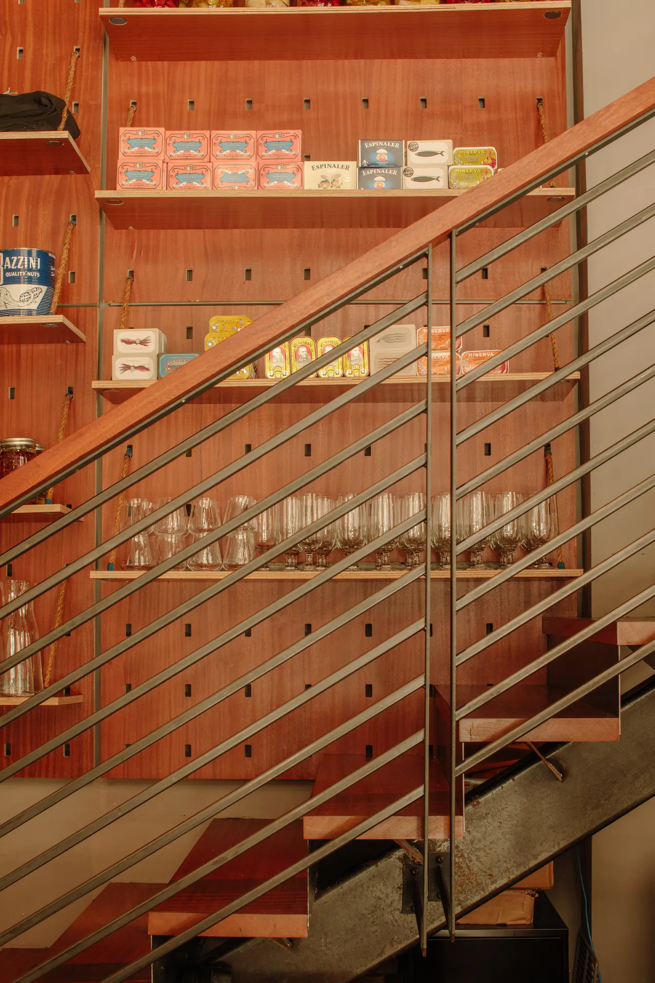 A steel stair with a rod balustrade crosses the shelving rather than being walled off from it.