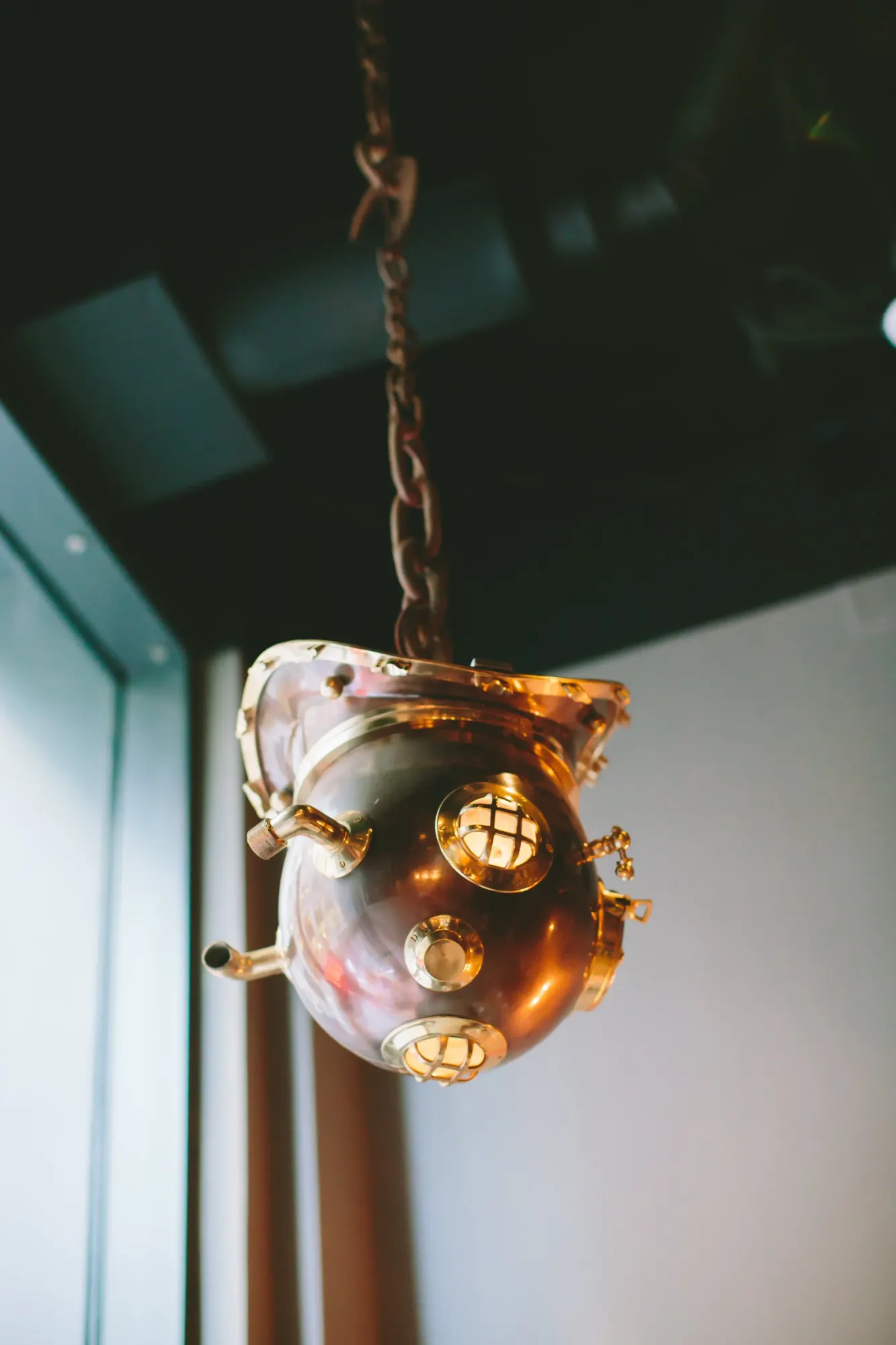 A copper diving helmet hung on a chain as a light.