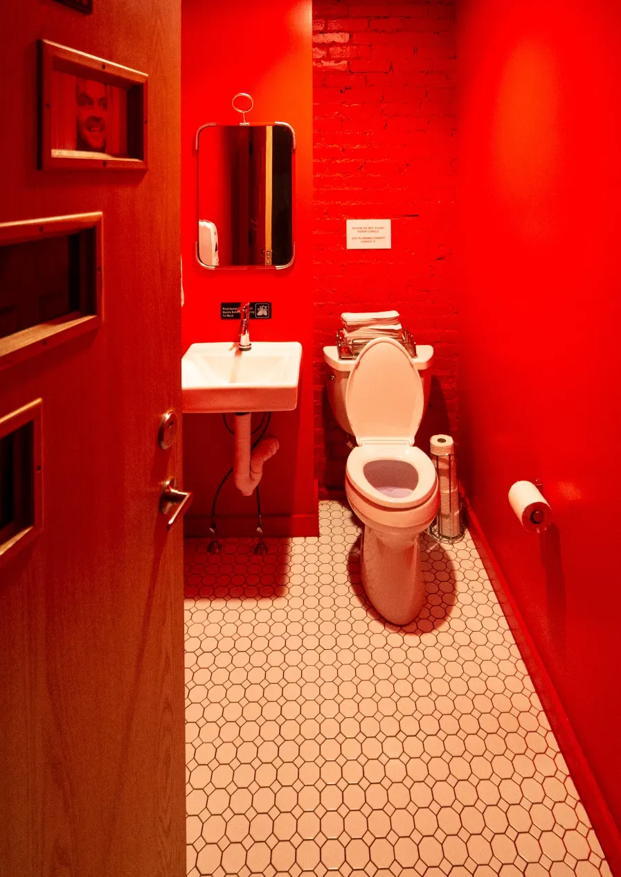 A restroom painted bright red, with a patterned tile floor.