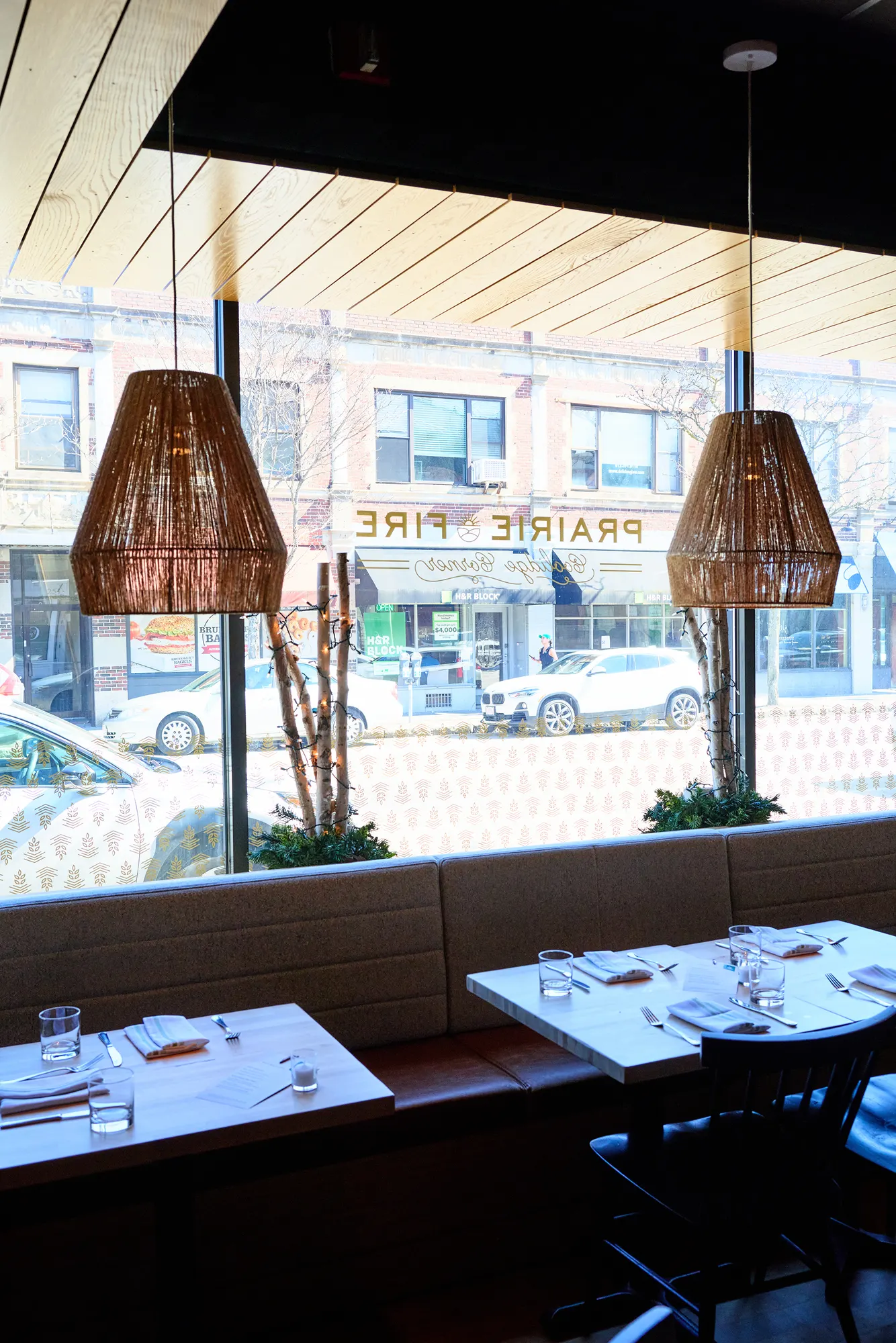 Tables along the front windows, with the restaurant's name on the glass and the street beyond.