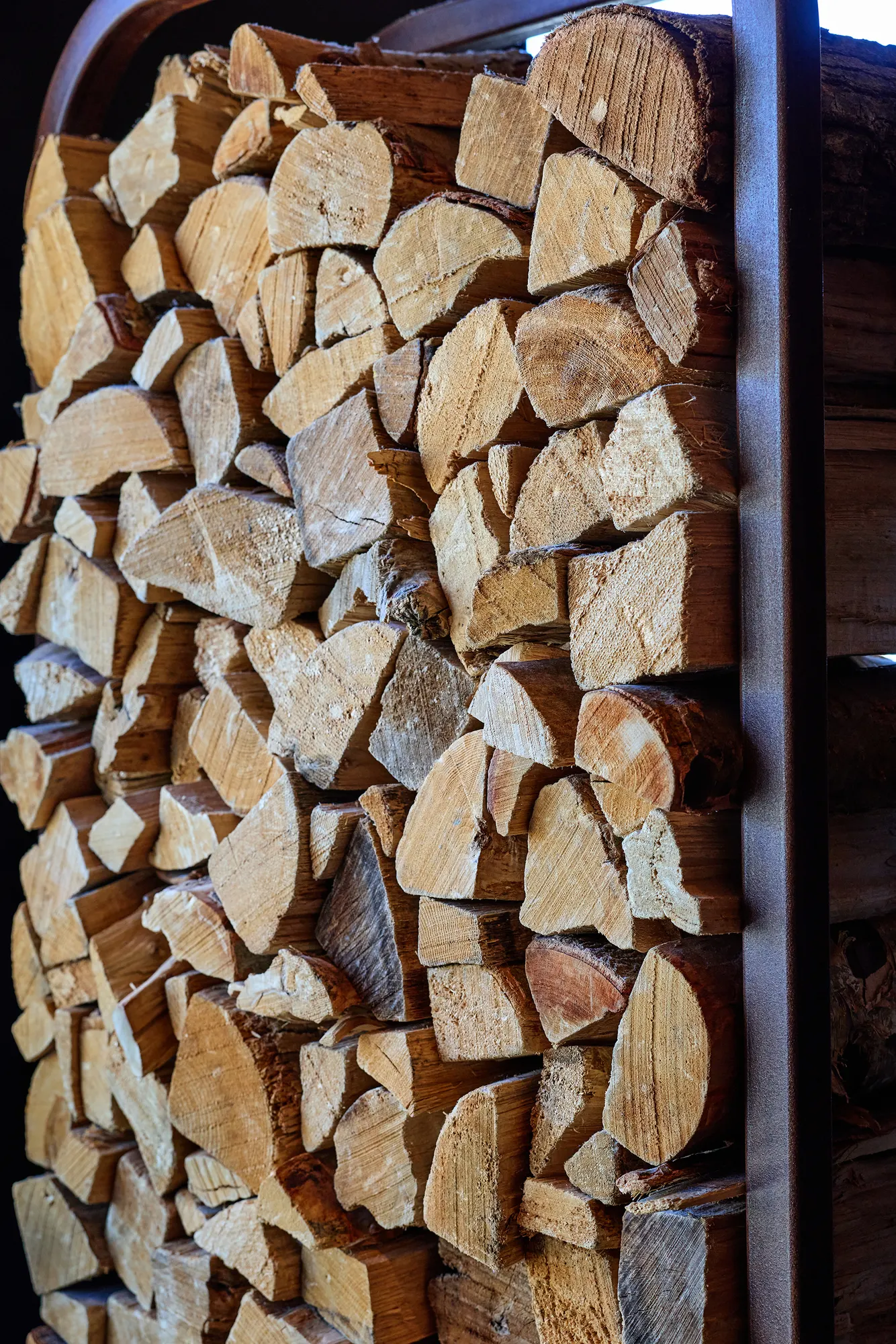Split logs stacked high in a steel-framed niche.