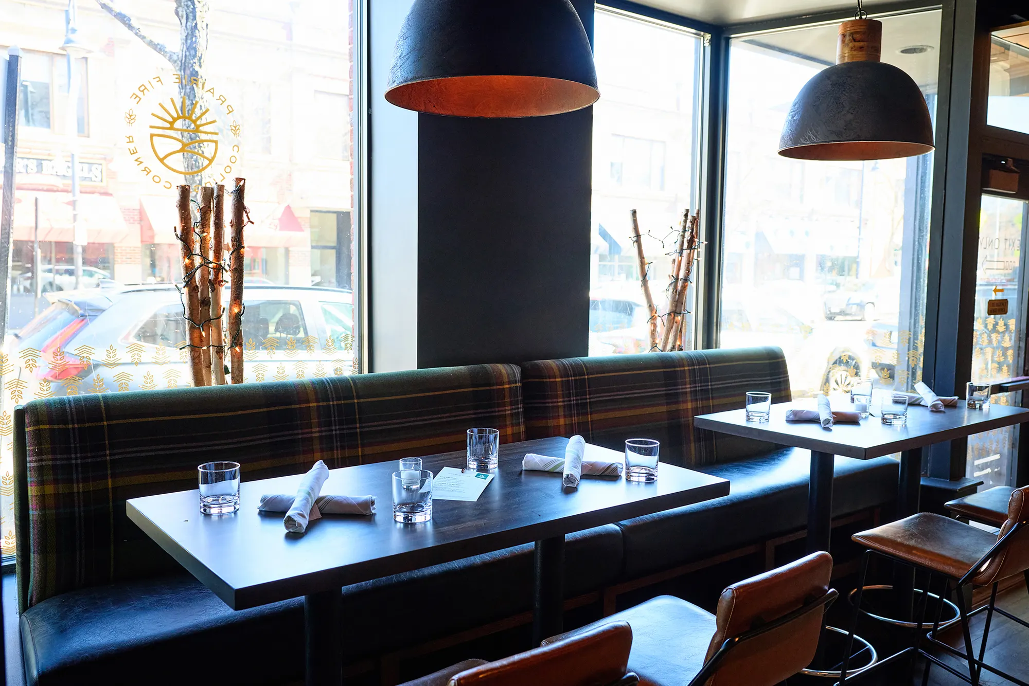 A plaid banquette under dark dome pendants, beside the front windows.