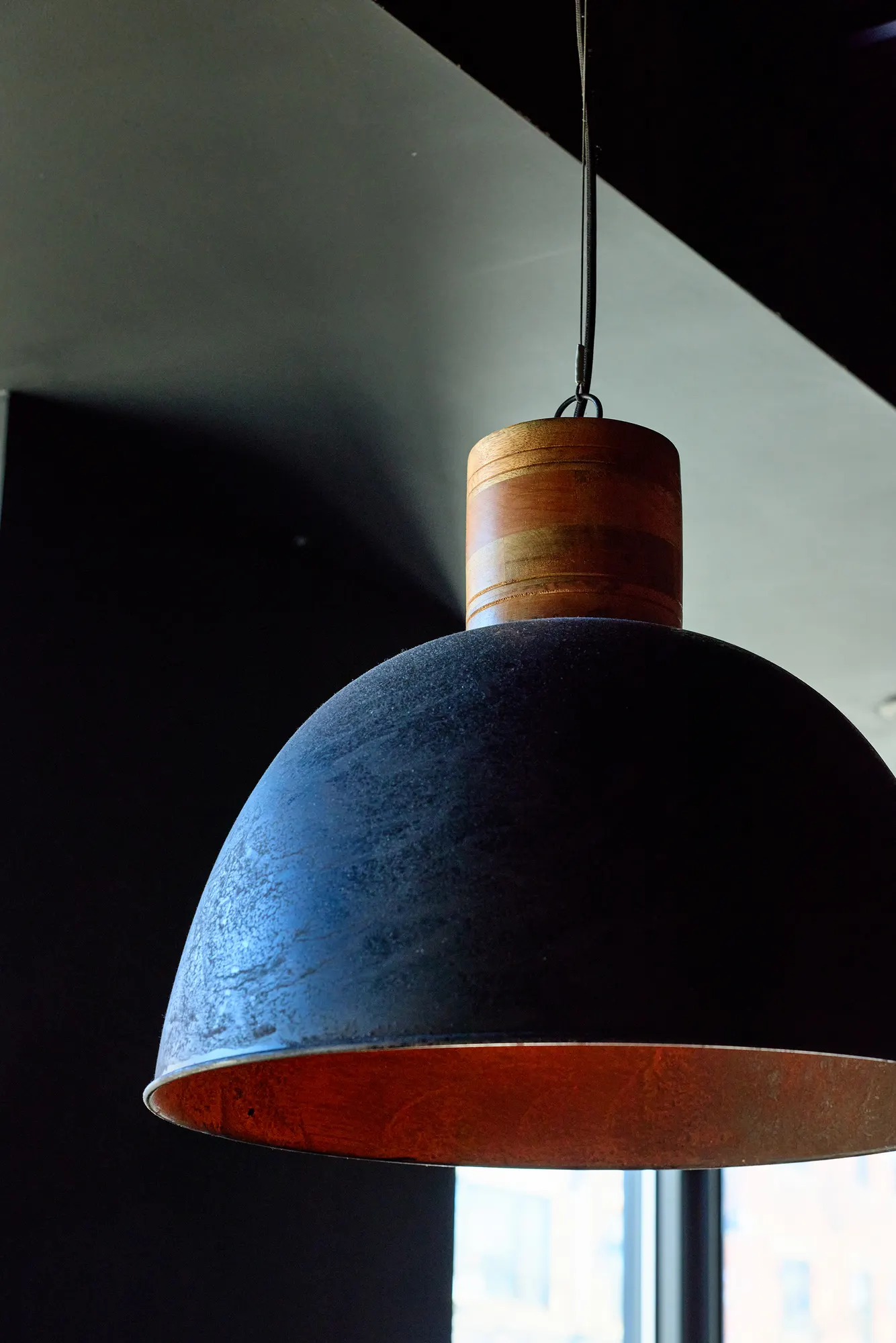 A dark dome pendant with a copper lining, close up.