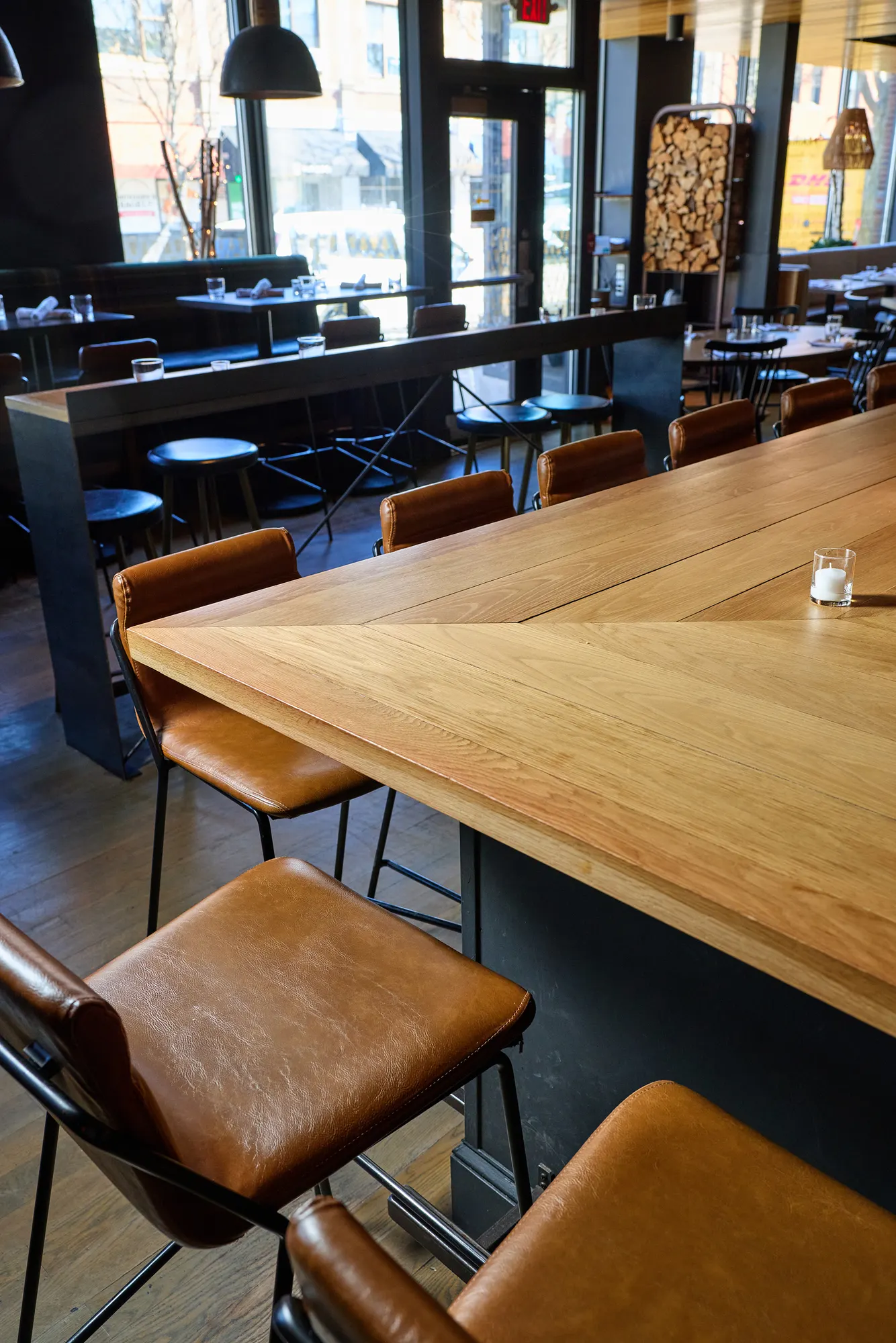 Leather stools at a pale timber high table, with the front of the restaurant beyond.