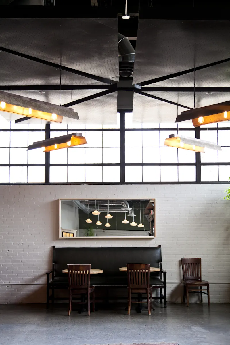 A banquette along the brick wall, below the industrial glazing and a ceiling fan.