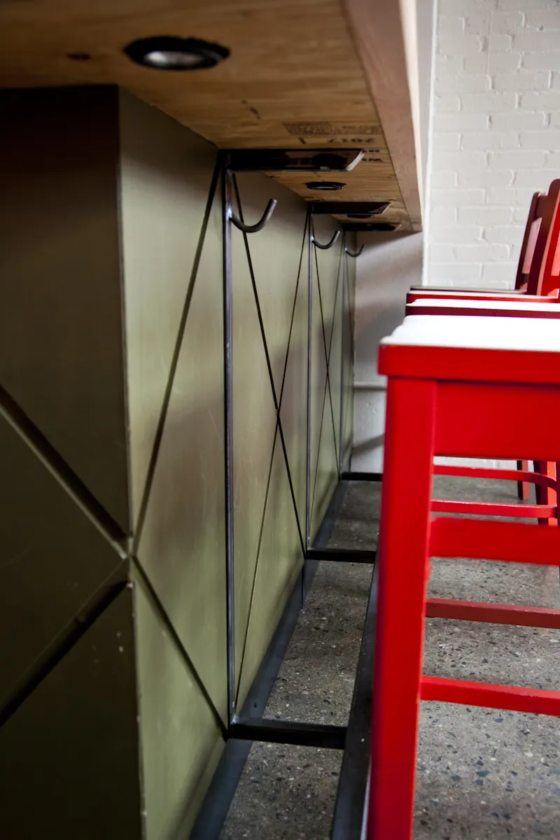 Steel rod crossed over the panelled bar front, with a footrail beneath.