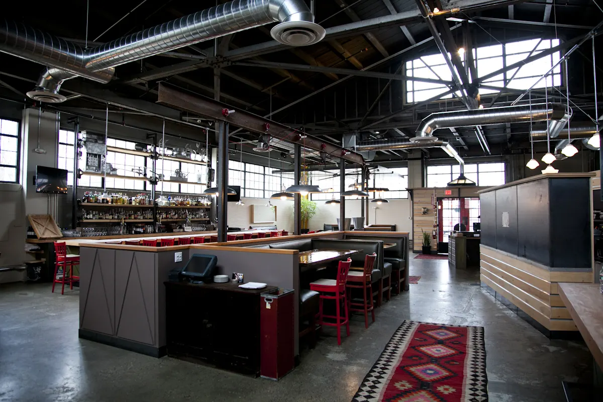 The room from the entrance: host stand, booths and the bar, under the open roof.