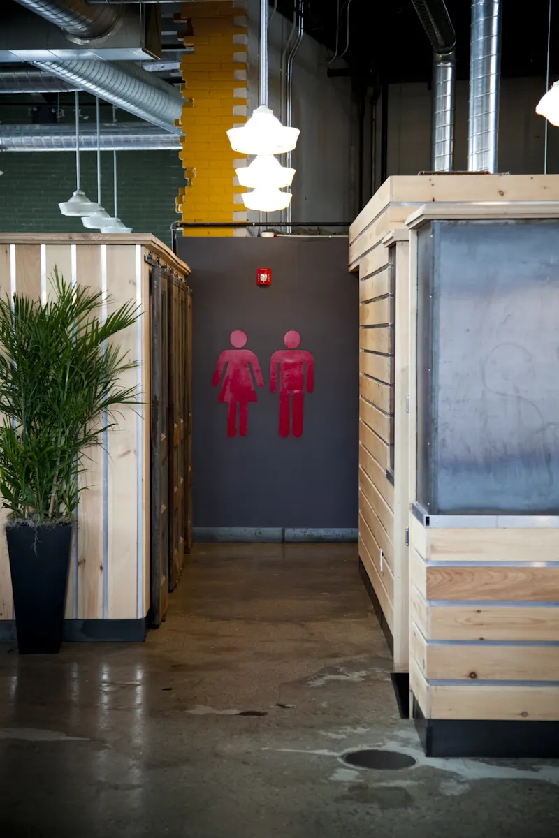 A passage between timber-clad walls, ending at the restroom door.