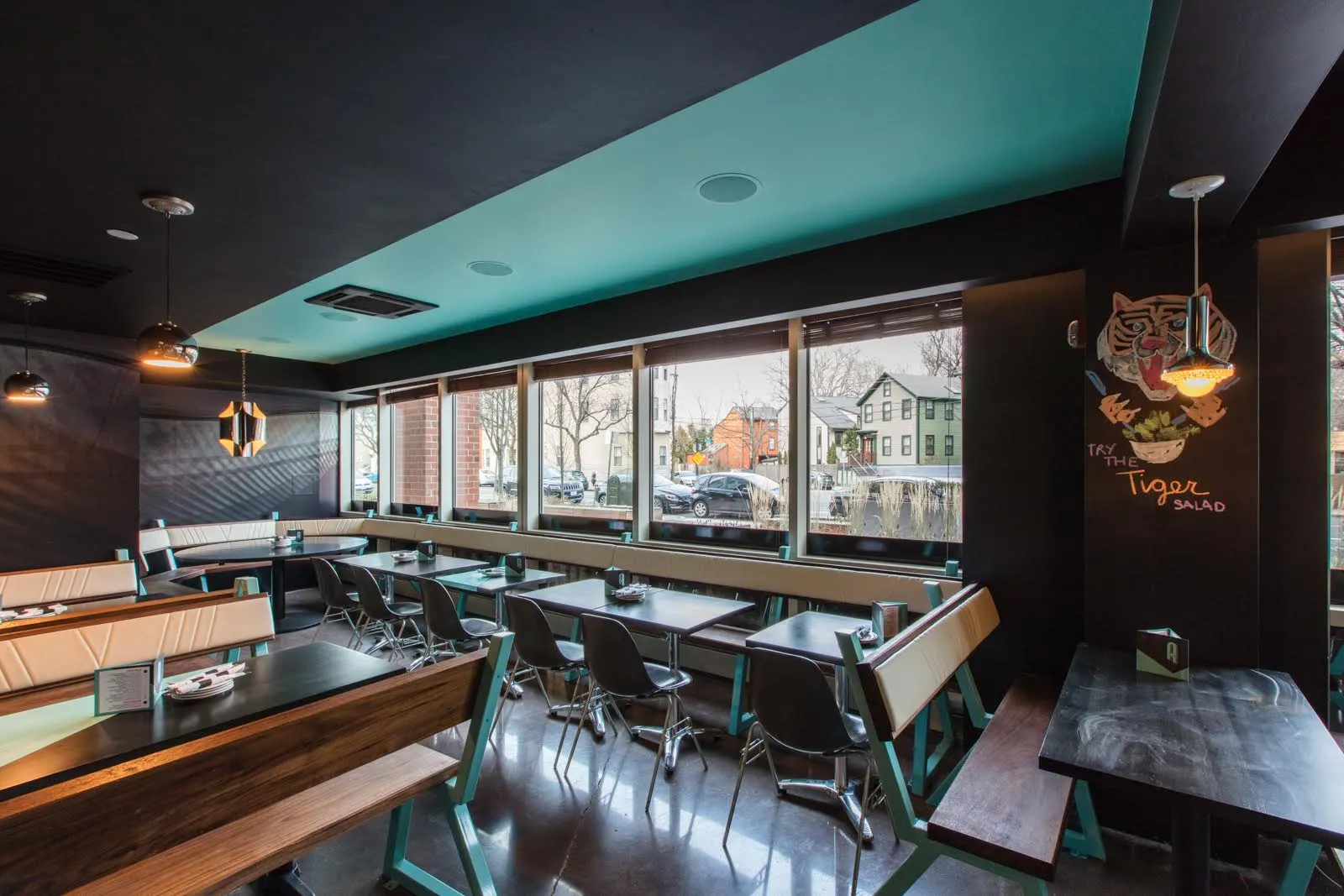 Tables and benches along the windows, with a tiger painted on the wall at the end.