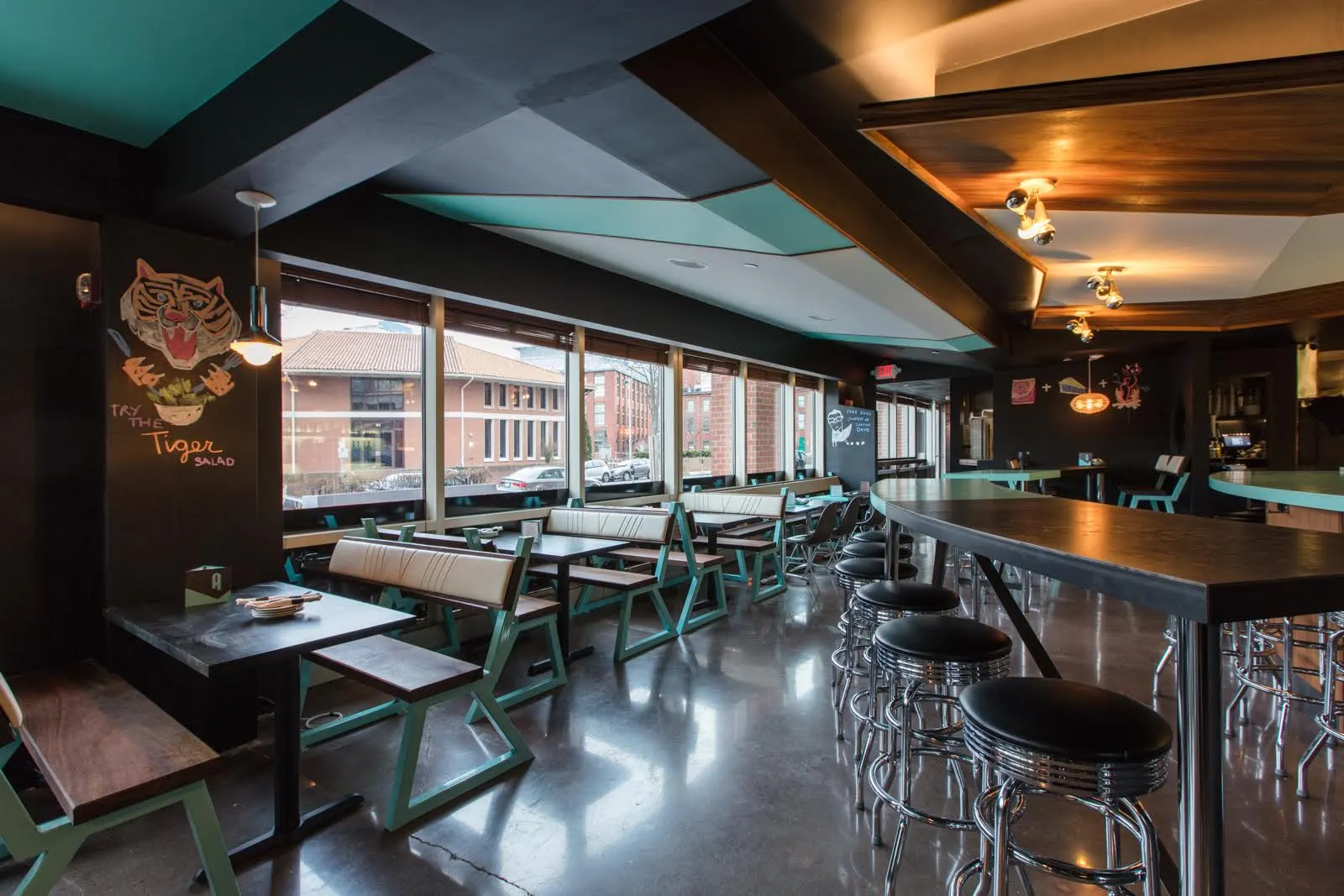 High tables and chrome stools by the windows, beside a painted tiger.