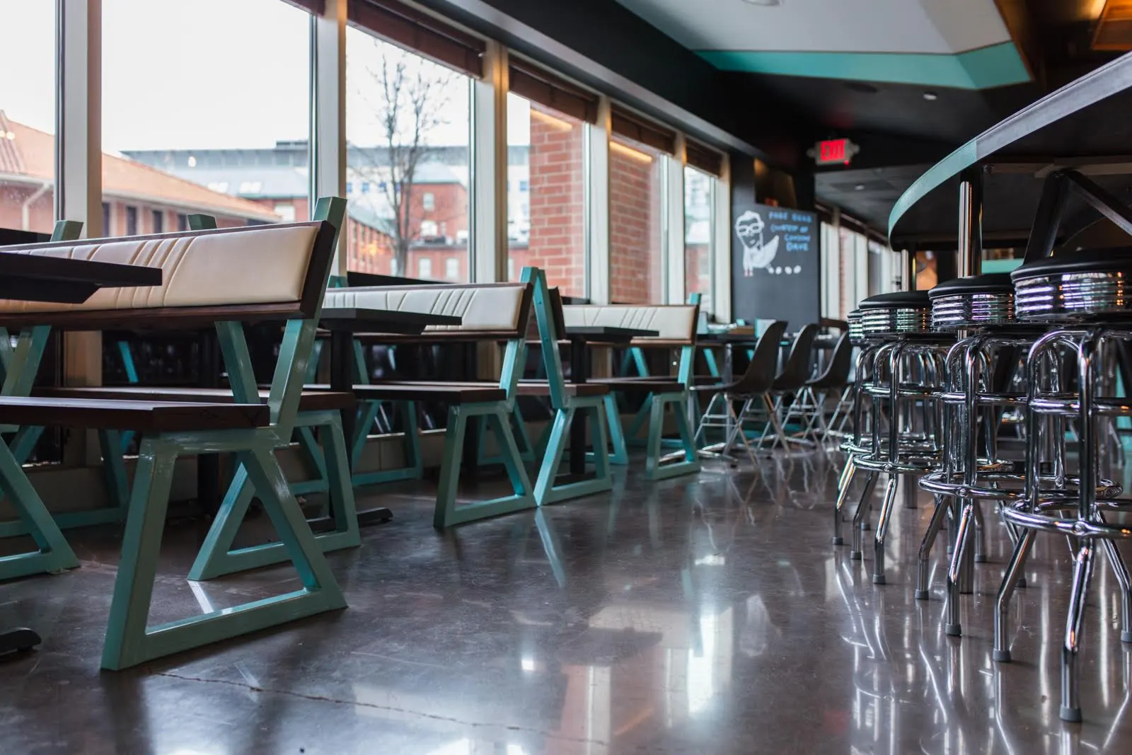 Teal-framed timber benches and chrome stools along the windows.