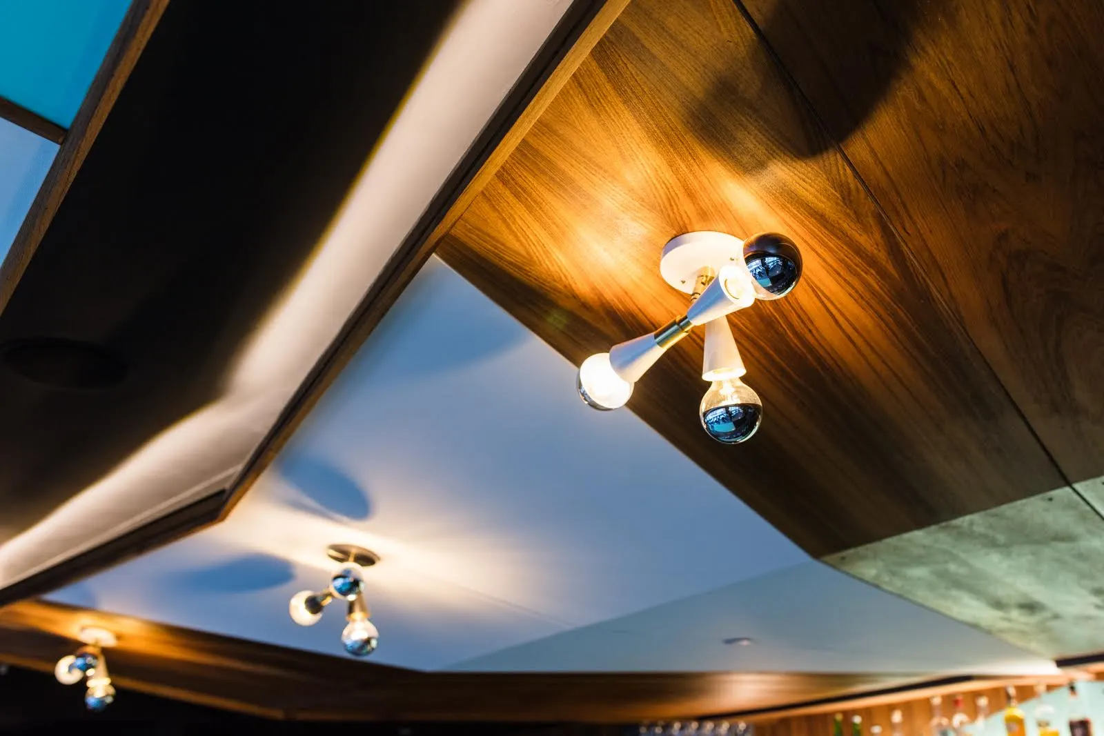 Timber ceiling panels and sky-blue soffits with brass light fittings, looking up.