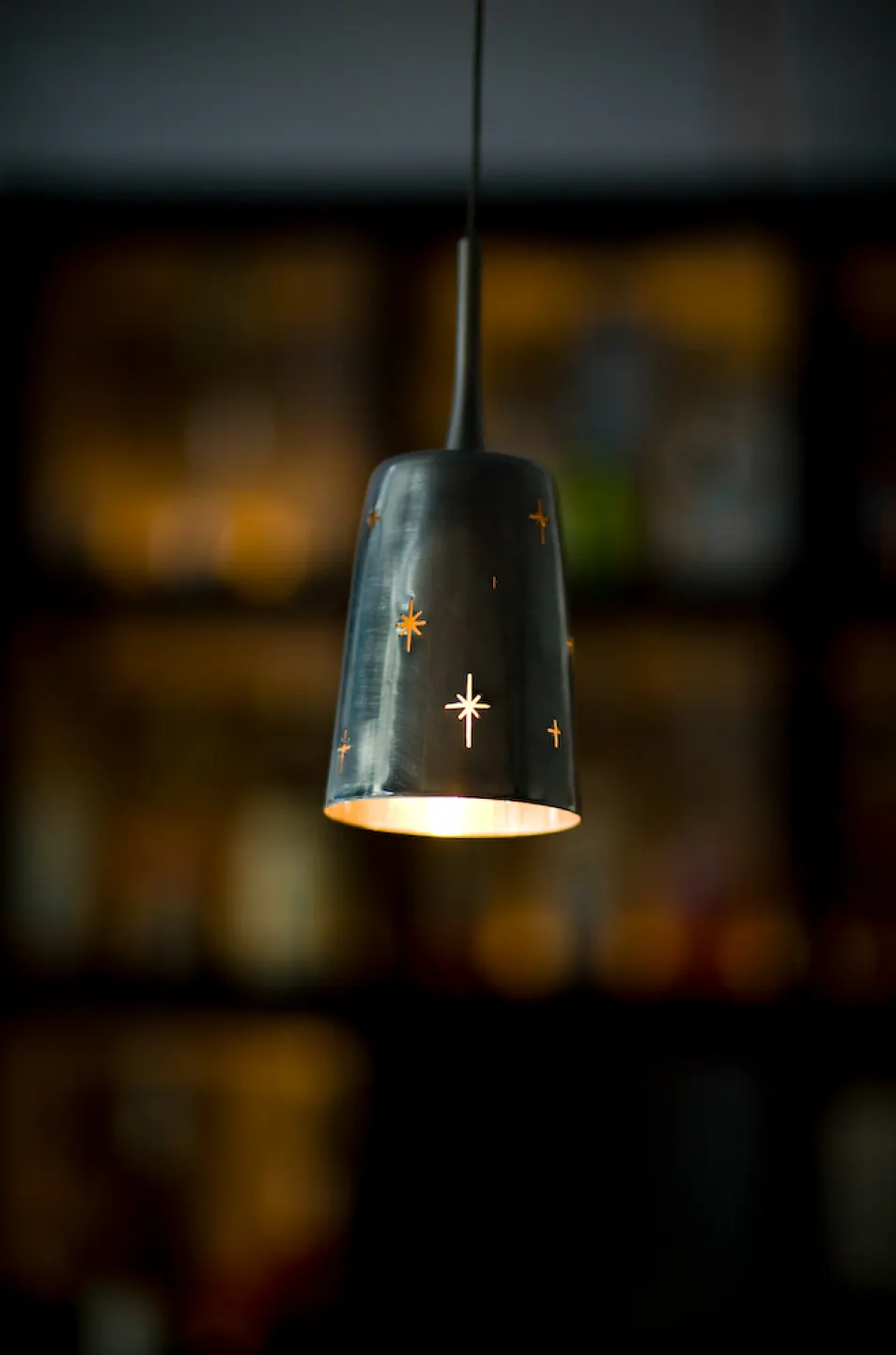 A dark pendant lamp pierced with stars.