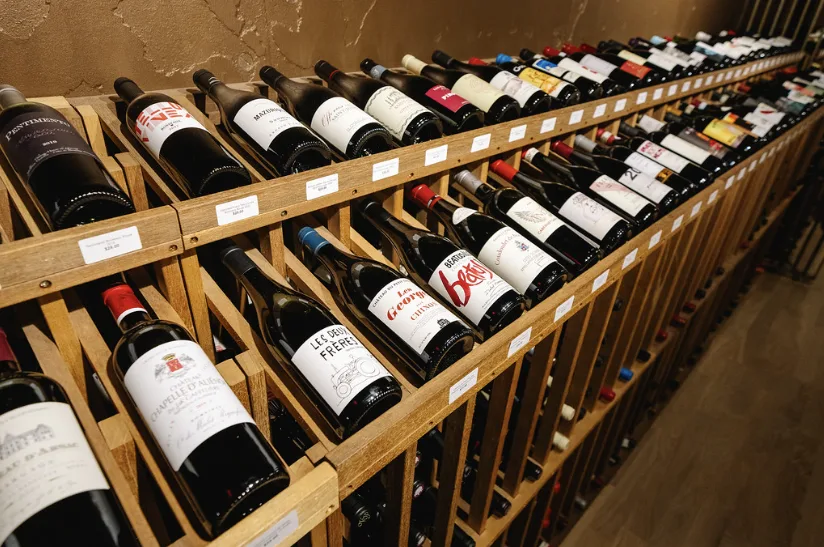 Wine bottles racked at an angle along a timber display.