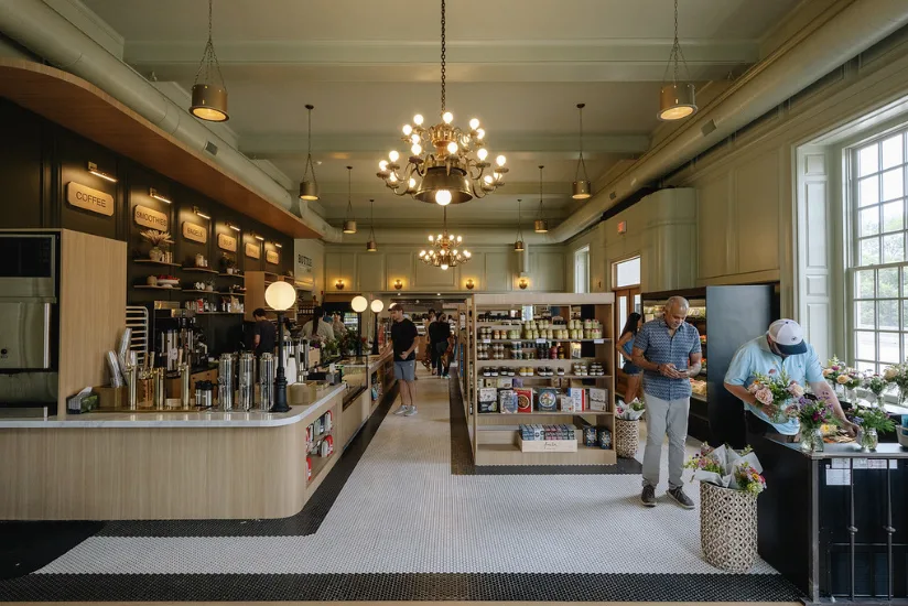 Two Pence Market, the long room with its counter, shelving and flowers under chandeliers