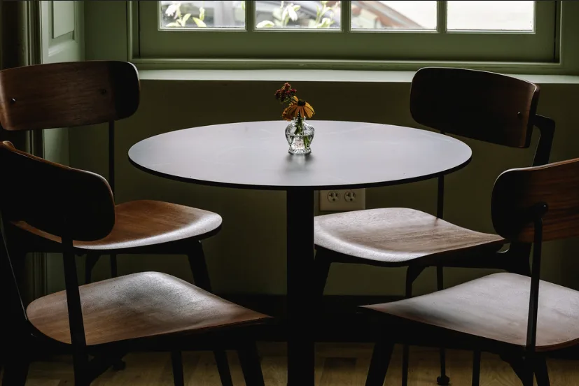 A round café table and four chairs under a window.
