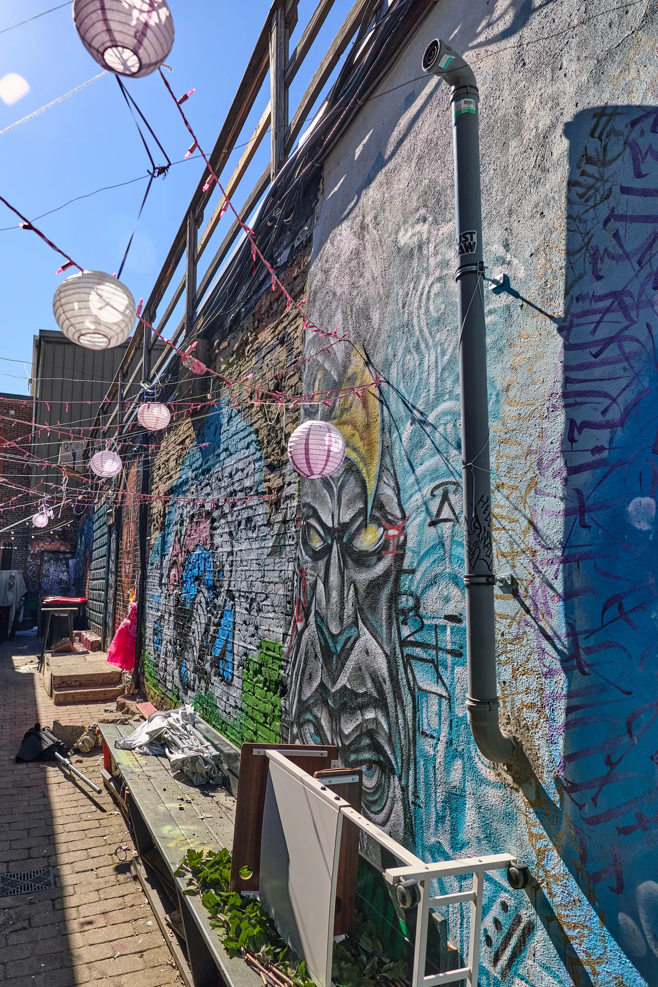 A narrow alley lined with murals and paper lanterns.