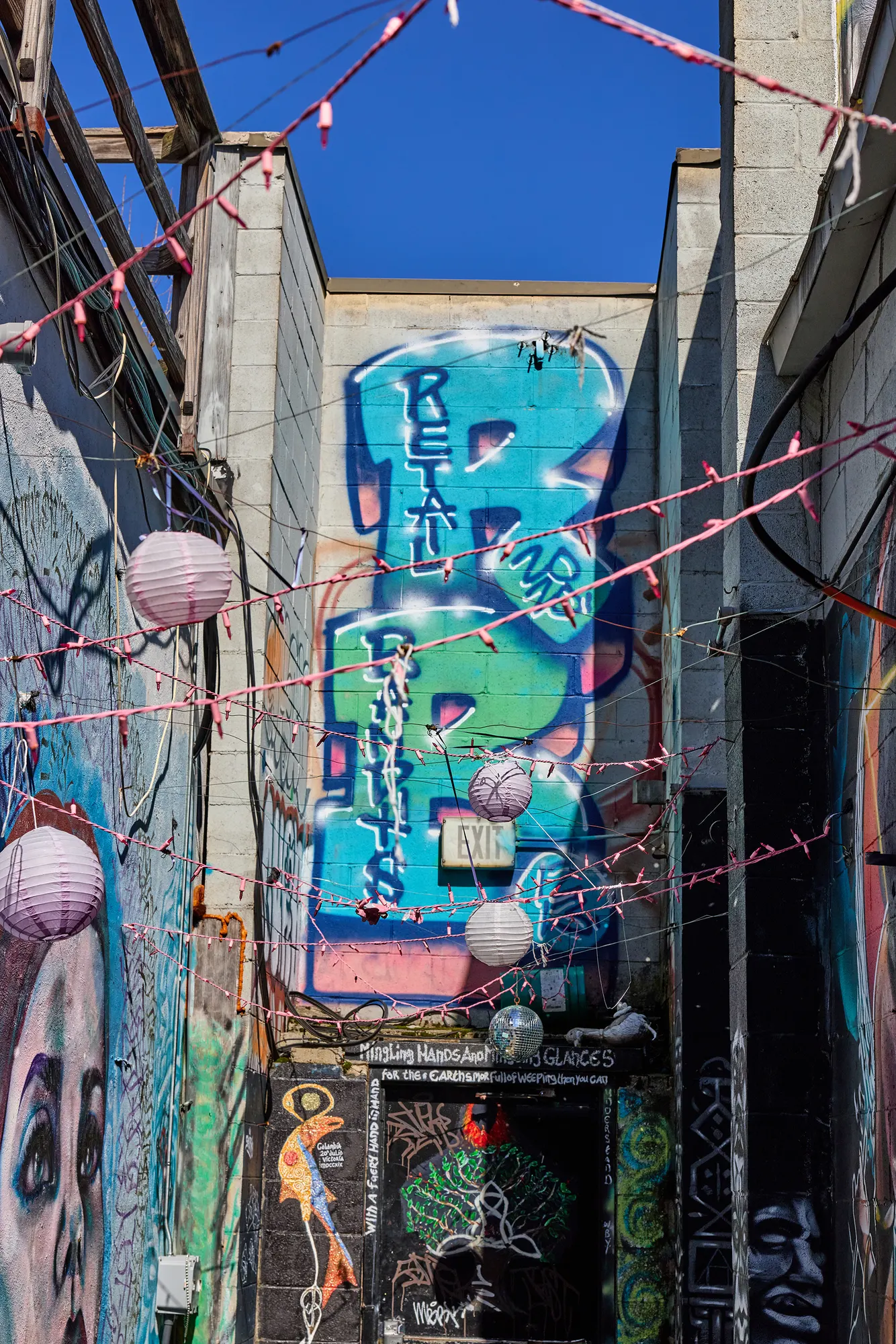 The end of the alley: a mural of painted lettering above a doorway.