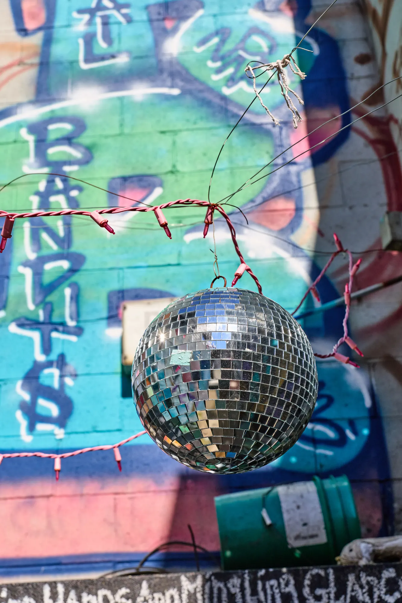 A mirror ball hanging in front of the painted lettering.