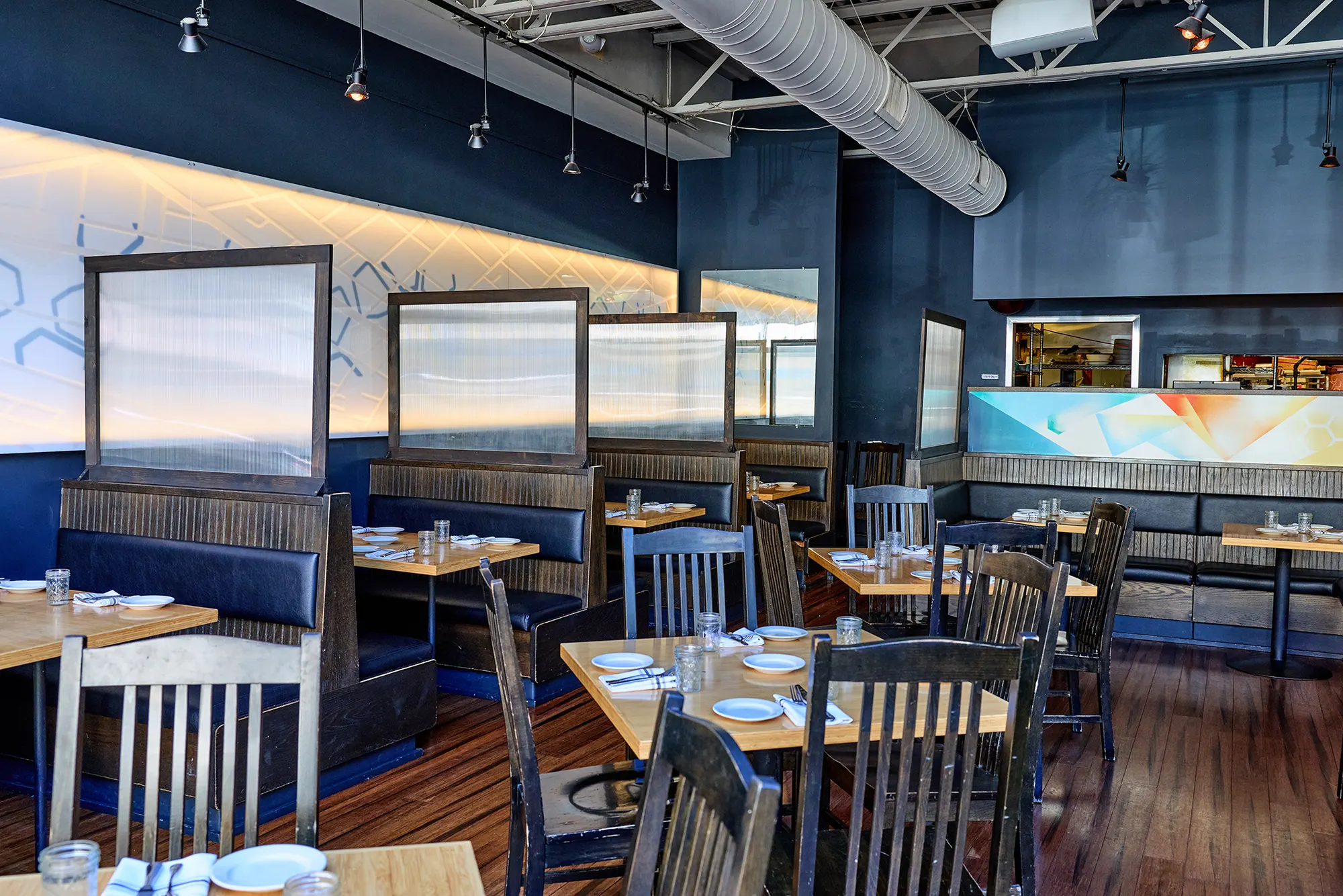 Booths divided by frosted screens along the backlit wall.