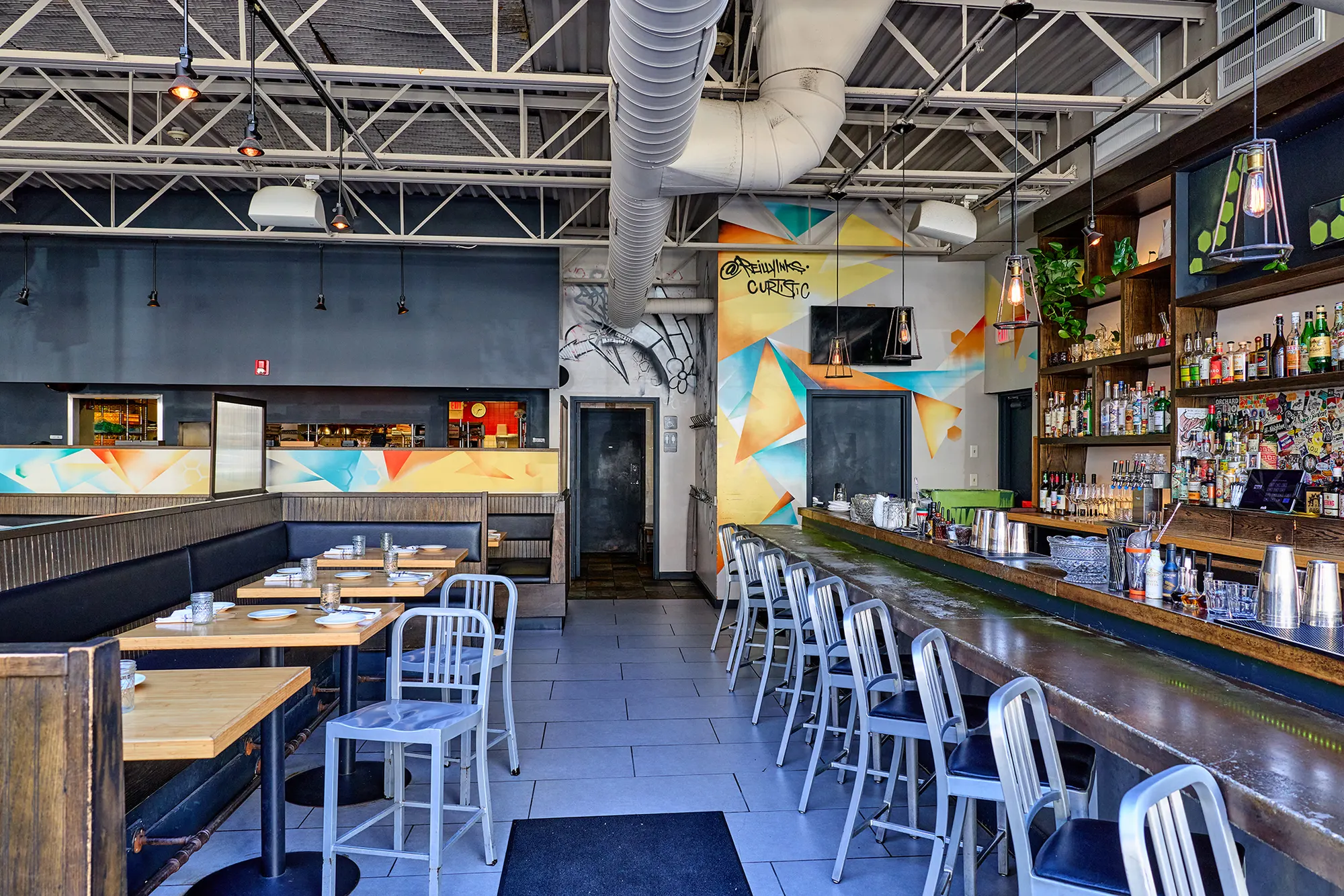 The long bar with steel stools and a colourful painted wall behind.