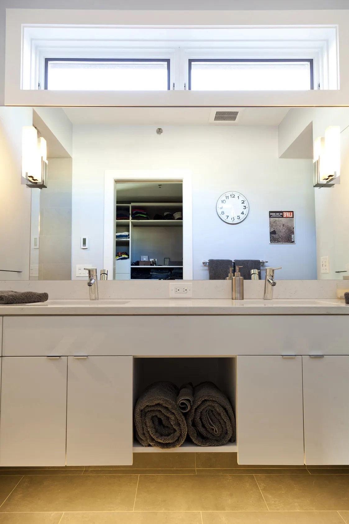 A long white vanity with two basins under a clerestory window.