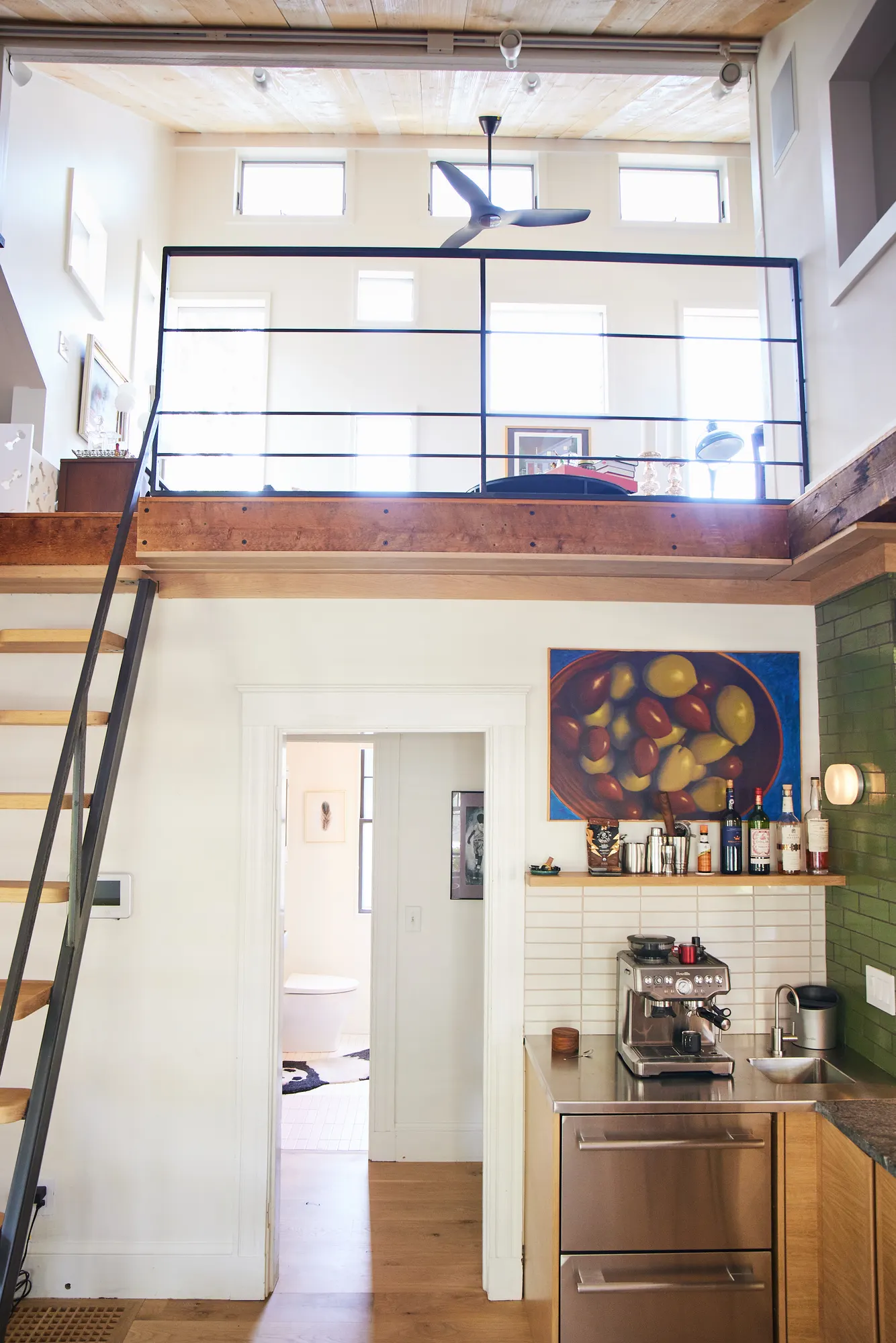 The kitchen wall and a doorway beneath the loft, with the ladder stair up to its rail.