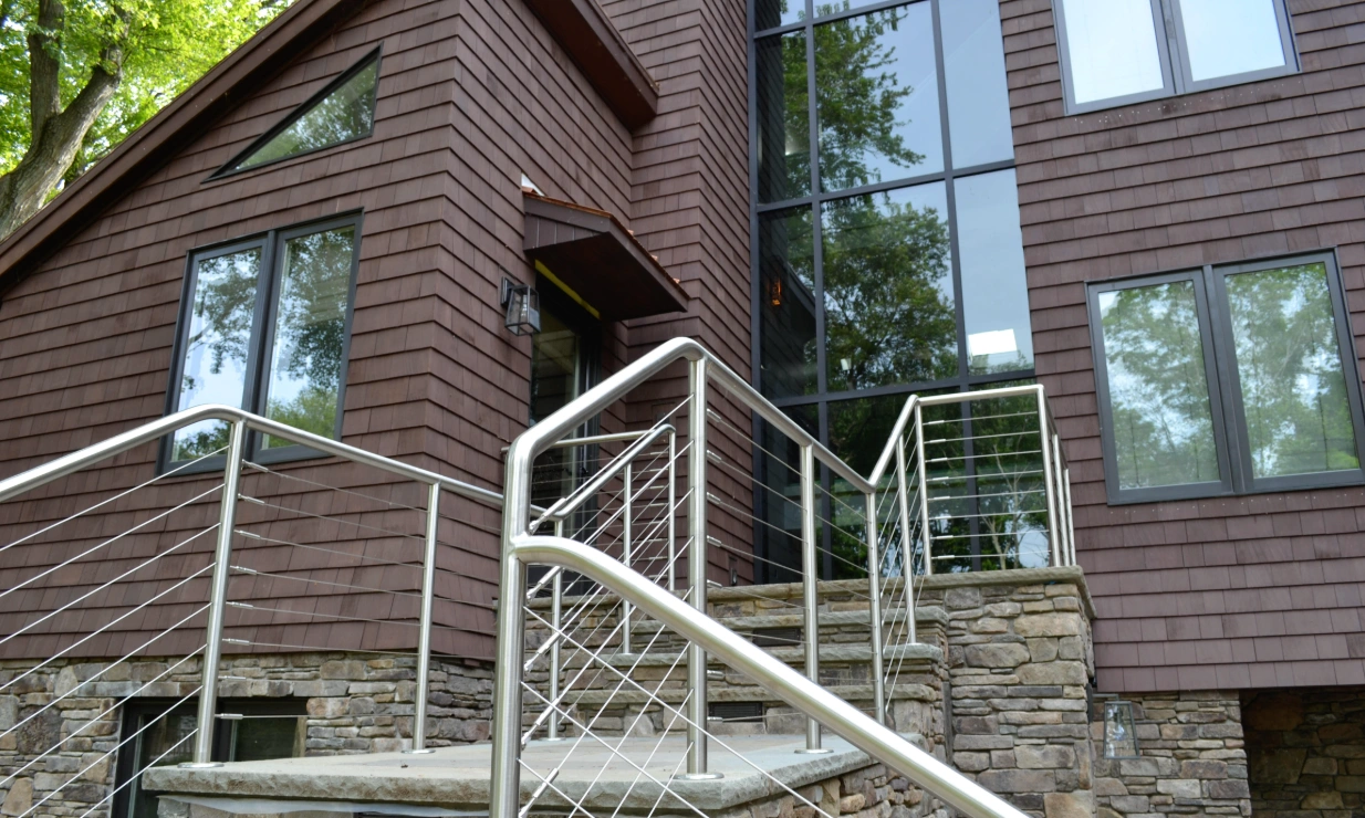 Stone steps with stainless steel cable rails leading up to the entry, beside the glazed tower.