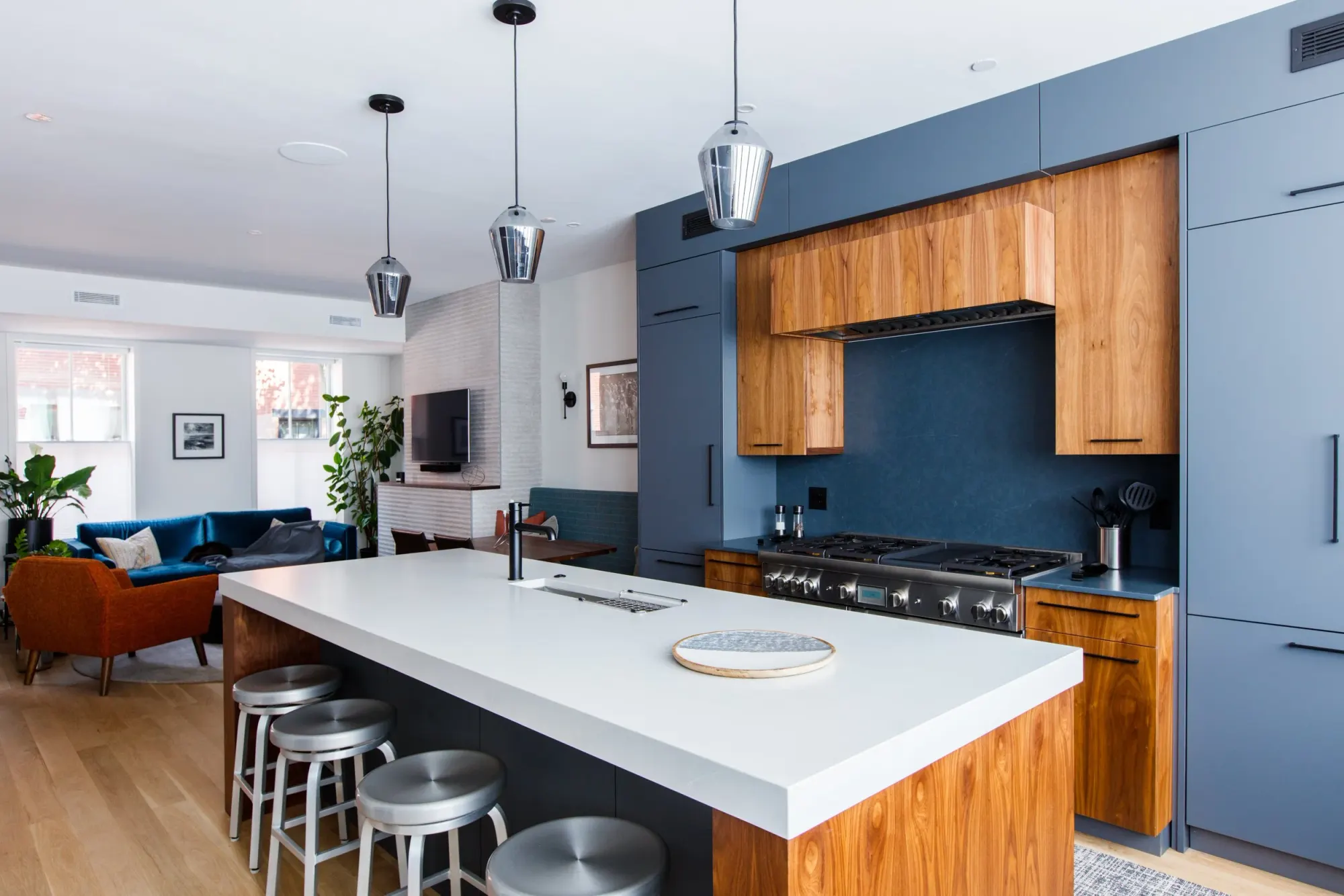 A walnut island with a white top, in front of a wall of blue cabinetry.