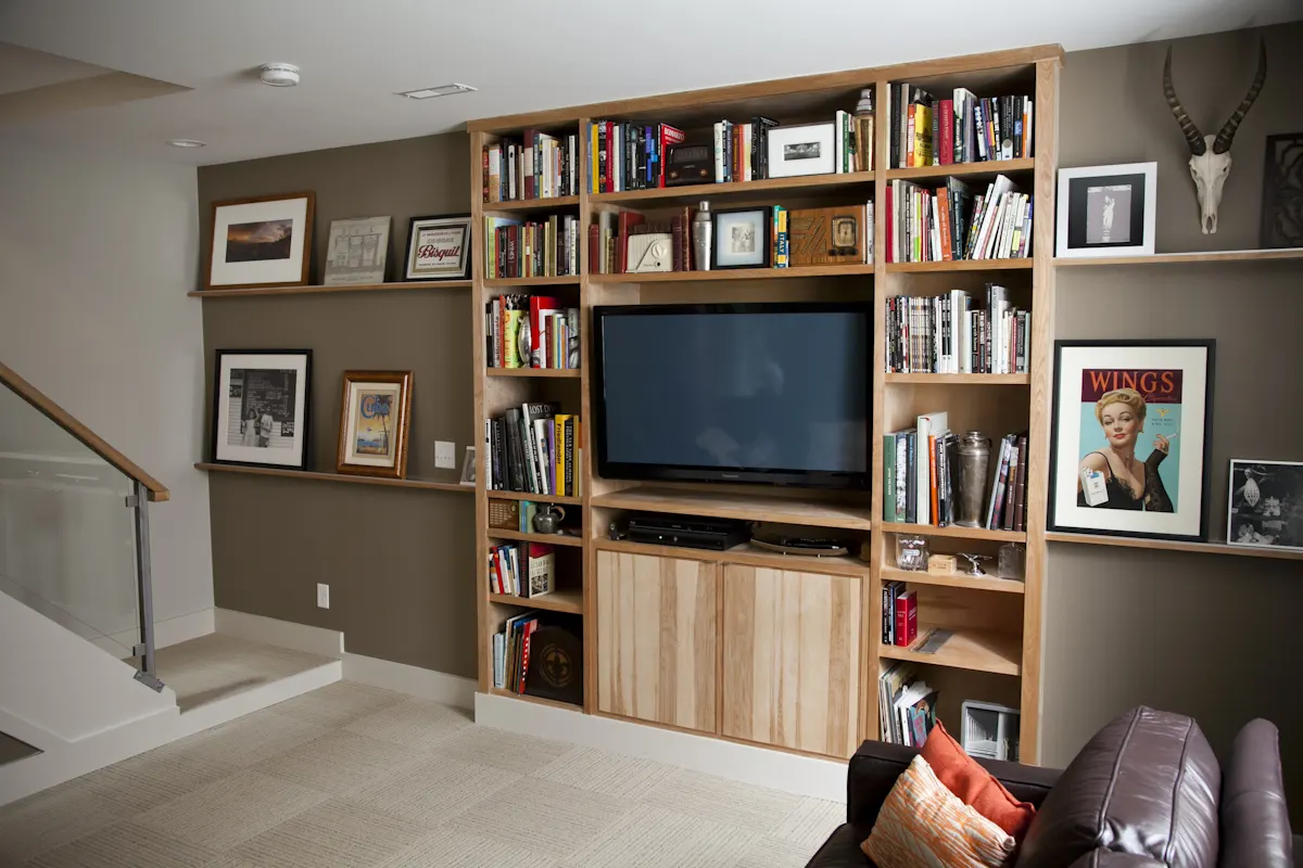Clyde Street: a wall of built-in bookshelves around a television, with framed pictures along a picture rail and the stair at the left