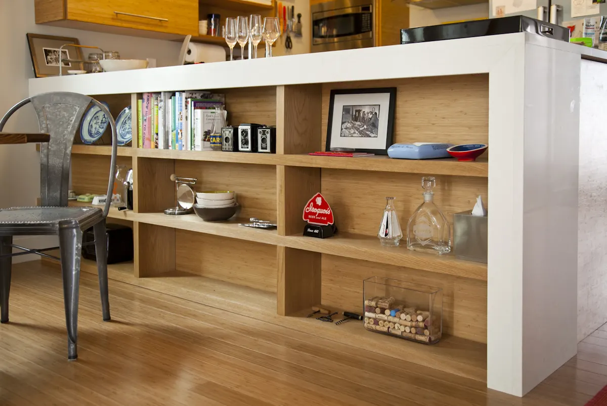 Open shelving built into the back of a white kitchen counter, with a metal chair beside it.
