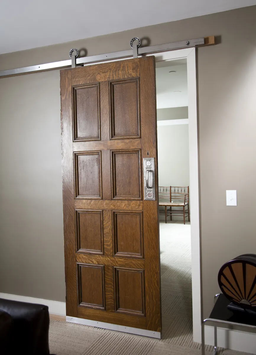 An old panelled timber door hung on a steel barn-door track.