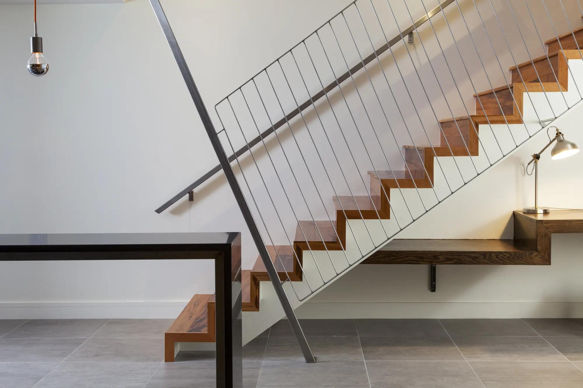The timber stair and rod balustrade, with a floating timber desk beneath and a lamp.
