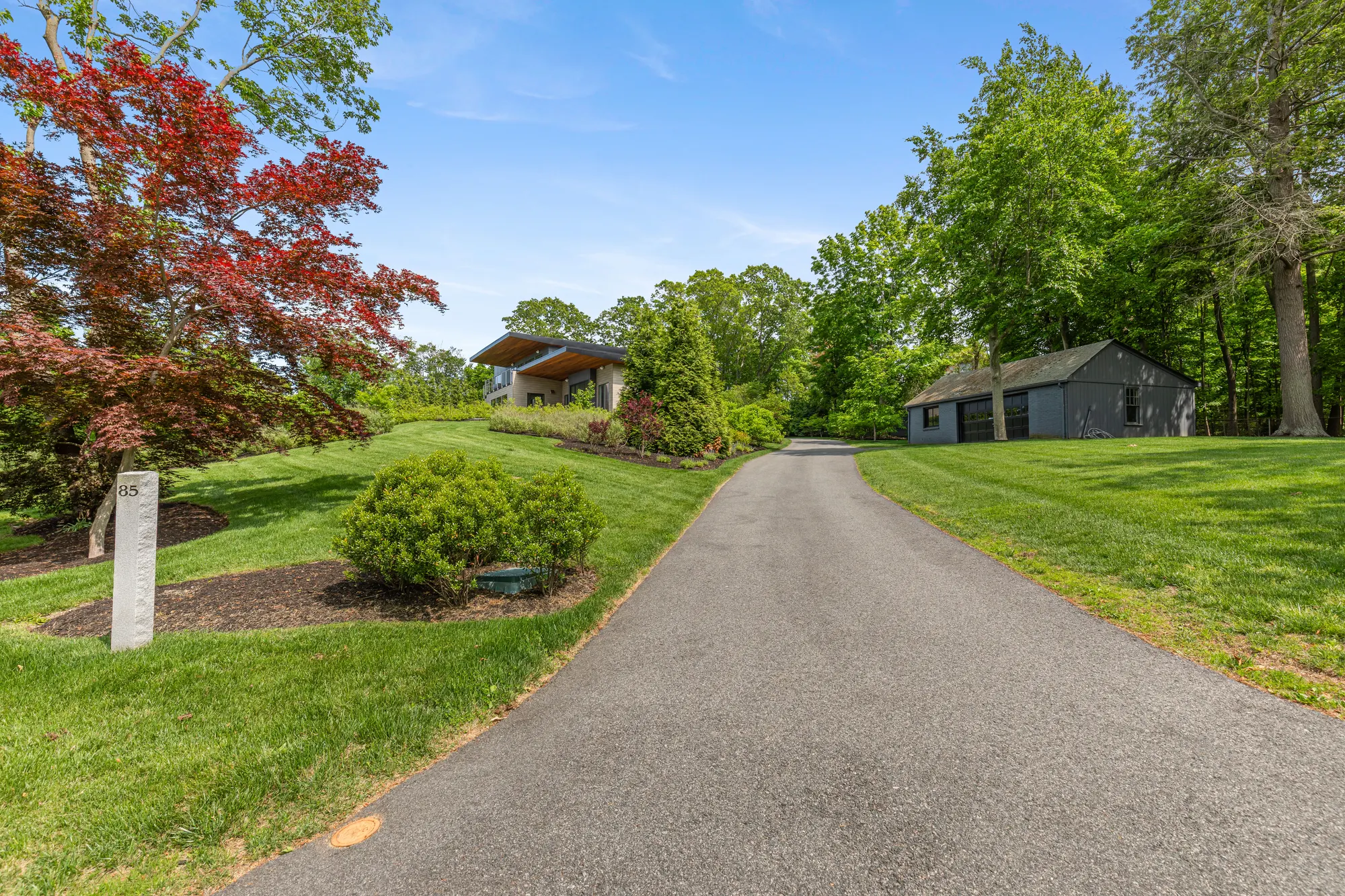 The drive running between lawns toward the house and the garage, a red maple at the left.