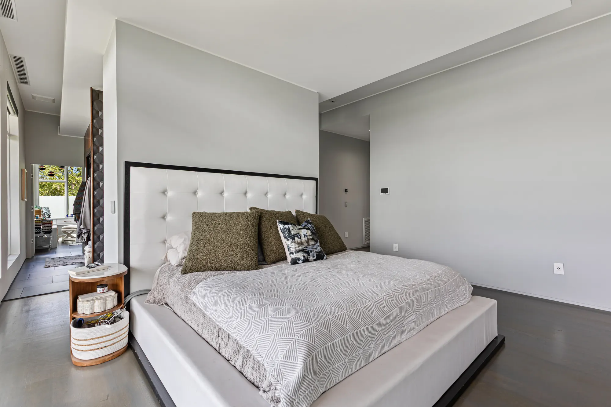 The bed against a white wall, with doors to the hall and the bathroom beside it.