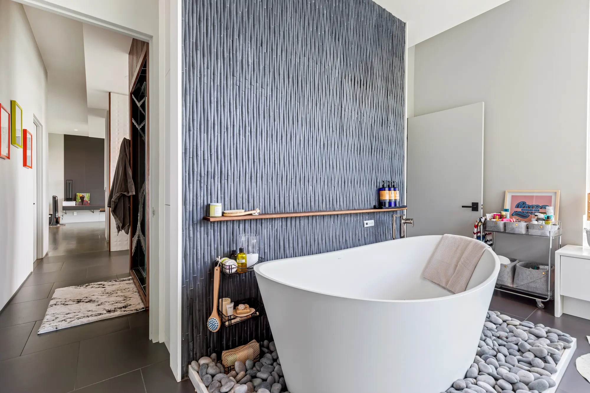 The tub on its river stones against the blue wall, with the closet through the doorway beside it.