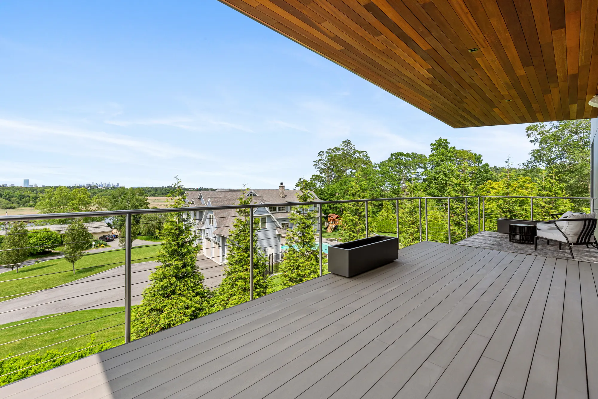 The upper deck and its cable rail, with a planter and chairs, over the neighbouring houses.