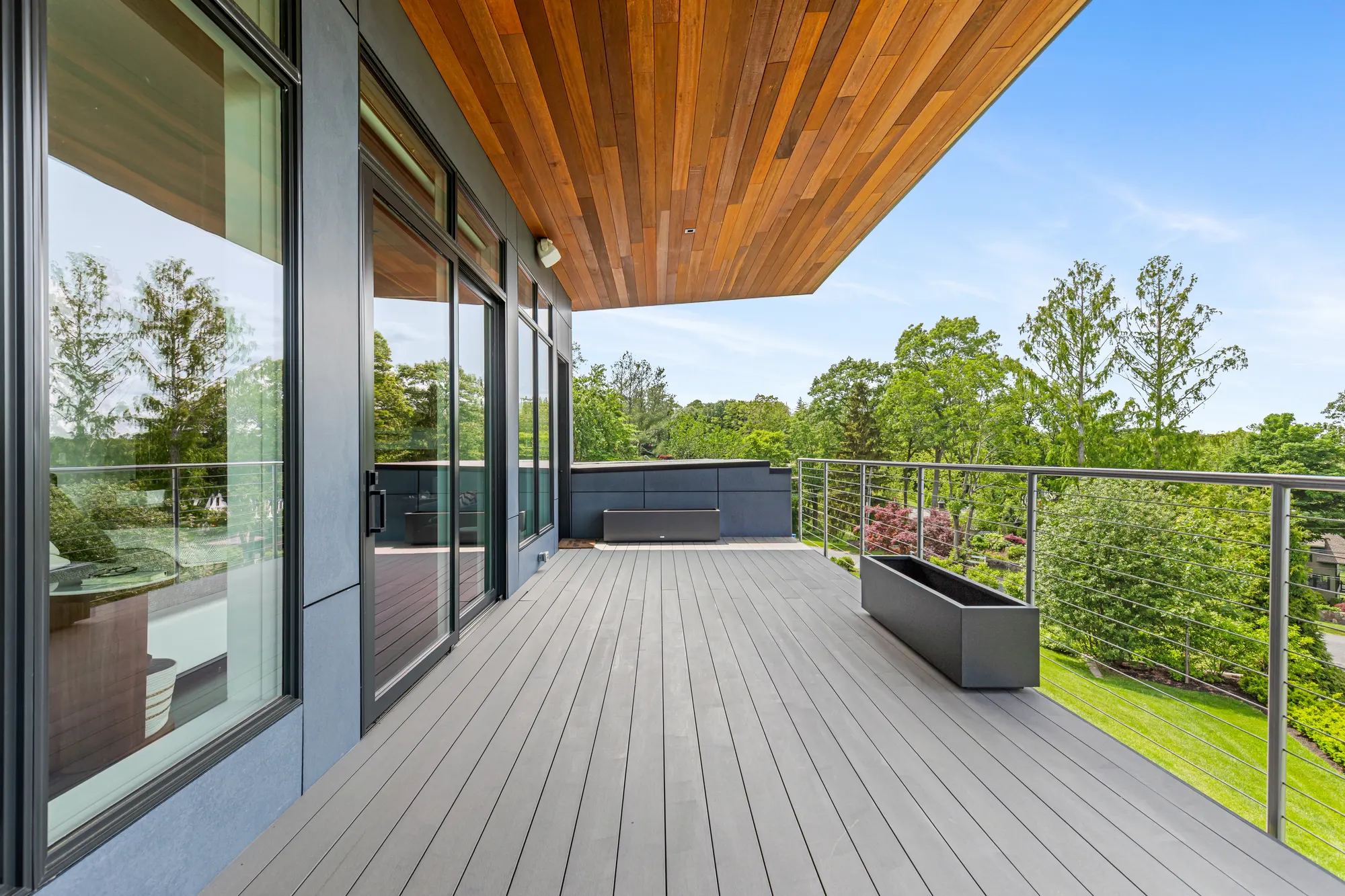 The deck running the length of the glass wall, with a planter at the rail.