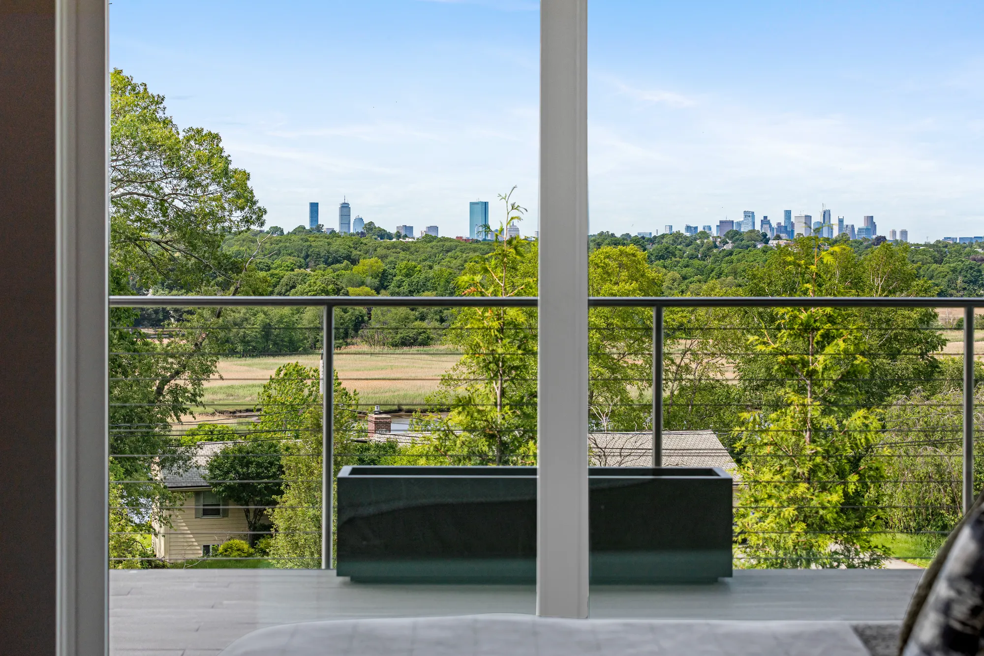 The Boston skyline over trees and fields, seen between the frames of the glass doors.