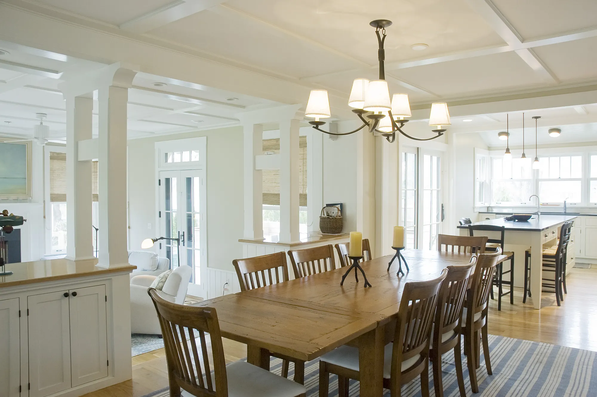 The dining table and chairs, with the kitchen at the far end under a coffered ceiling.