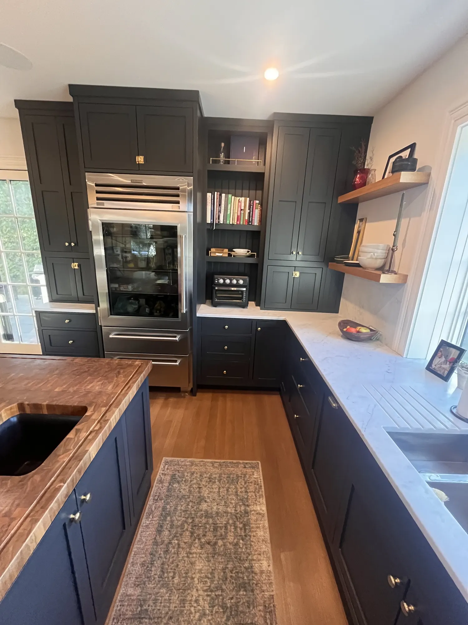 A glass-door refrigerator built in among tall dark cabinets, seen across the island's walnut top.