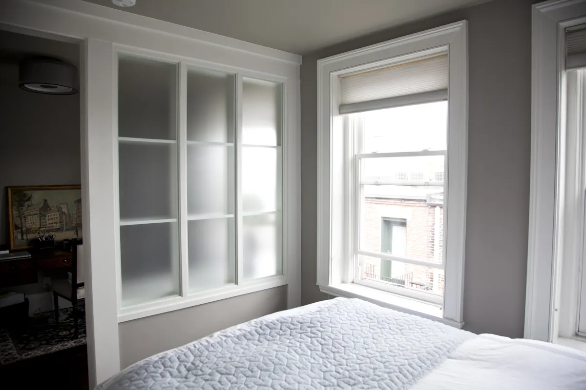 Frosted glass panes set into the wall beside the bed, with a window onto the street.