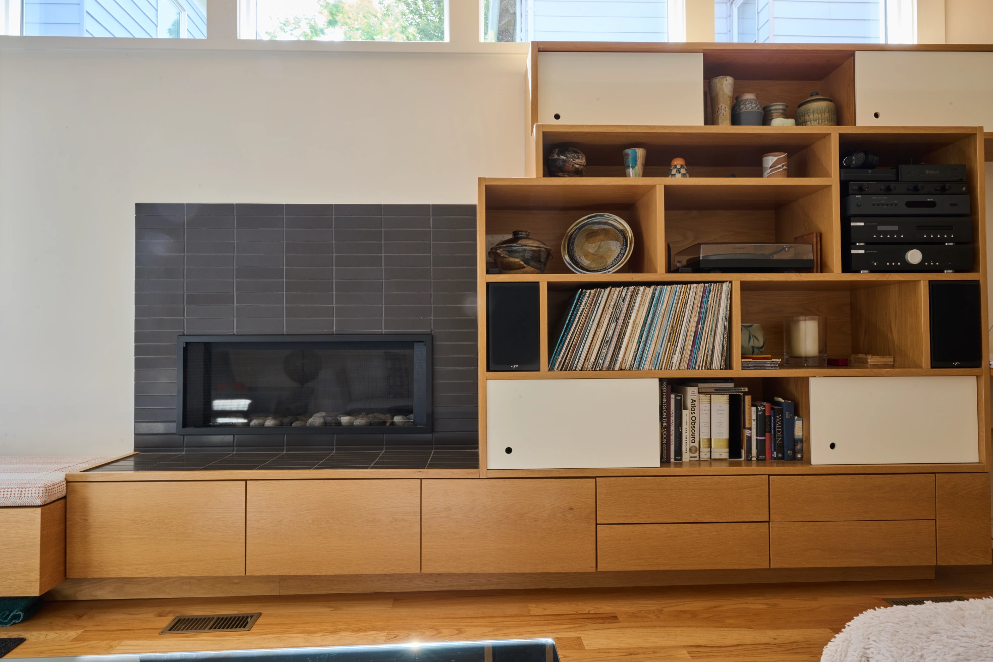 A tiled fireplace set into maple built-ins holding records, books and a stereo.