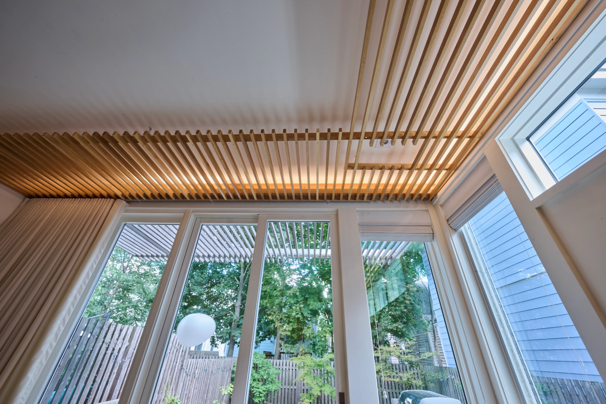 Timber slats running across the ceiling above tall windows onto the garden.